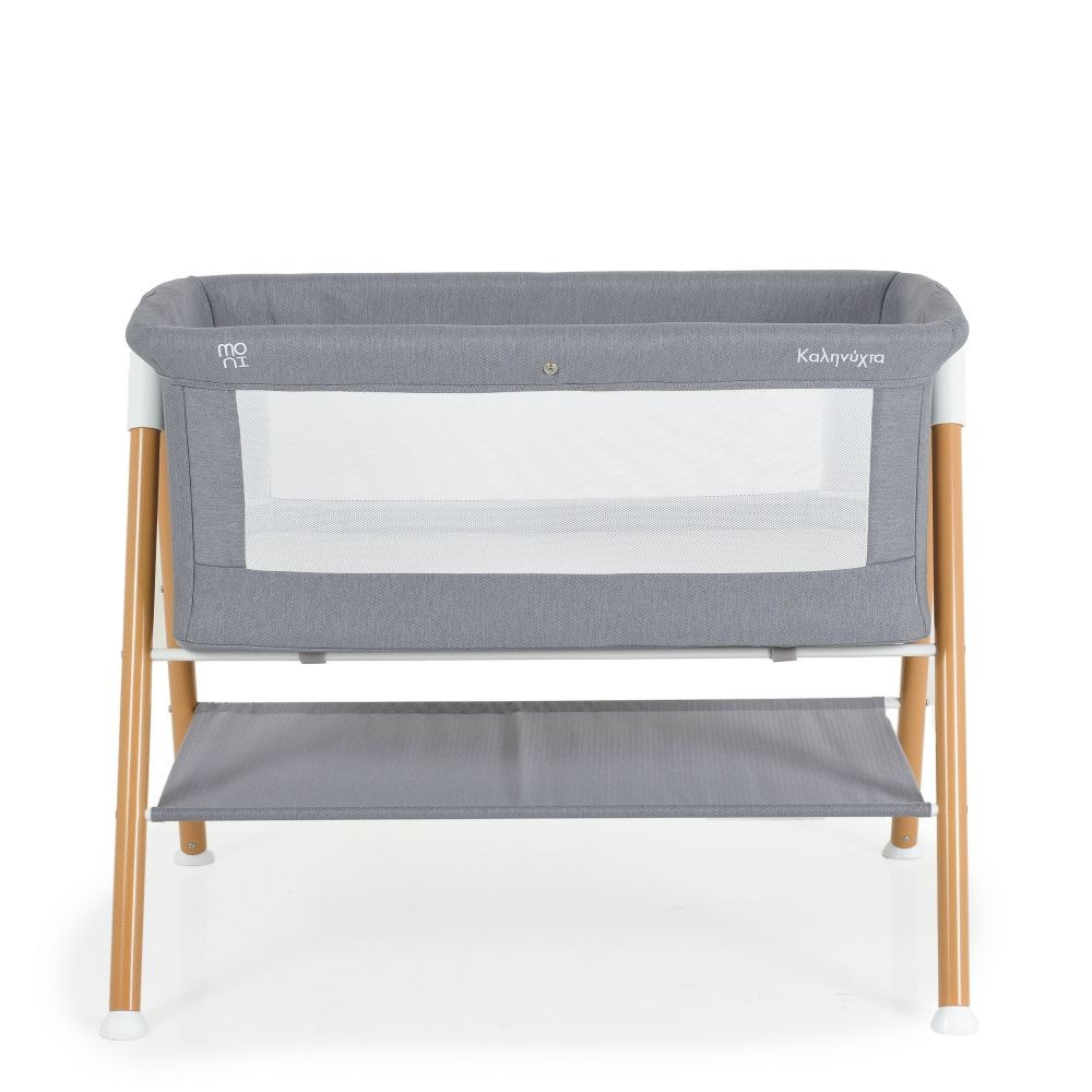 Cuna gris para bebés con malla blanca. Patas de madera y un estante de almacenamiento. Fondo blanco.