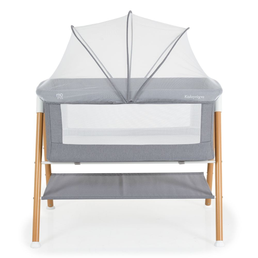 Cuna gris para bebés con mosquitera. Patas de madera, estante de almacenamiento. Fondo blanco.