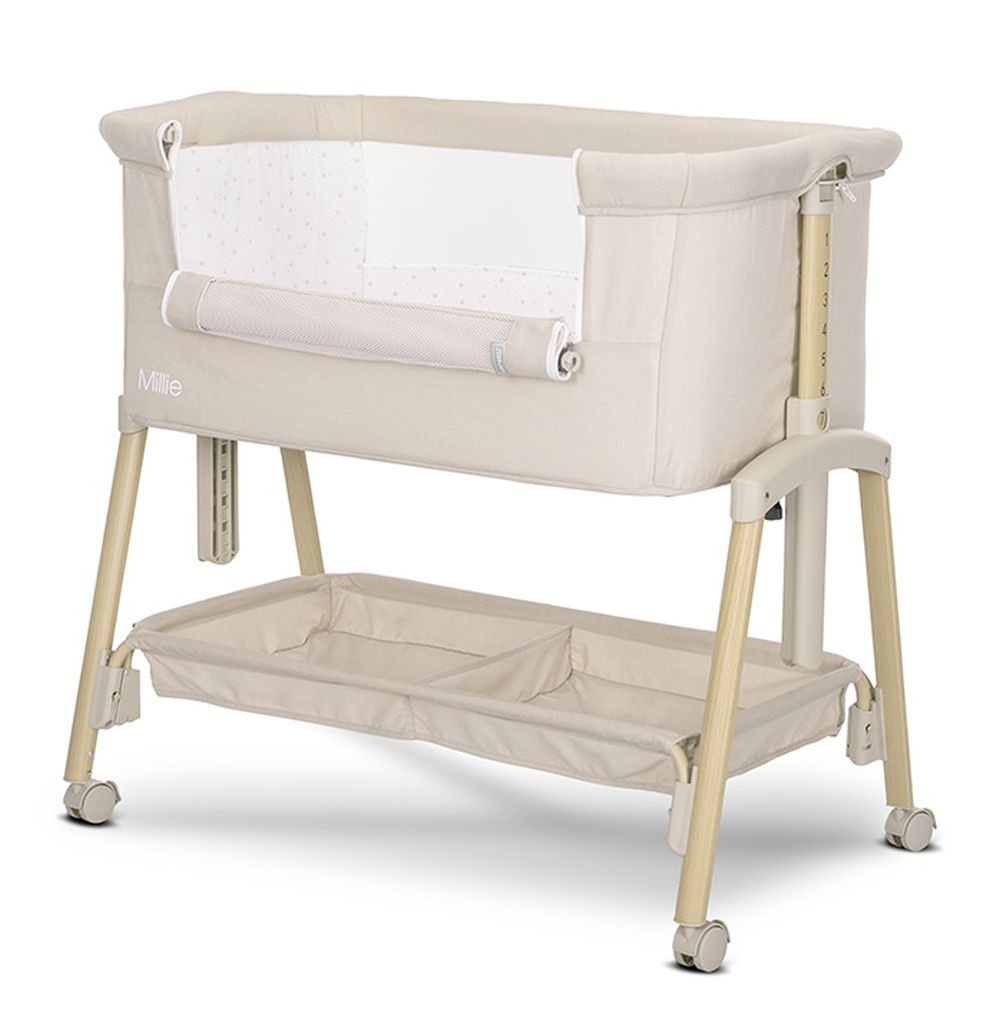 Cuna beige para bebé sobre un soporte con zona de almacenamiento. Fondo blanco.