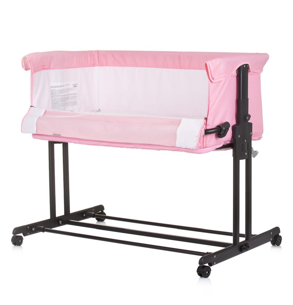 Una cuna rosa. La cuna tiene una cama blanca y un marco negro.