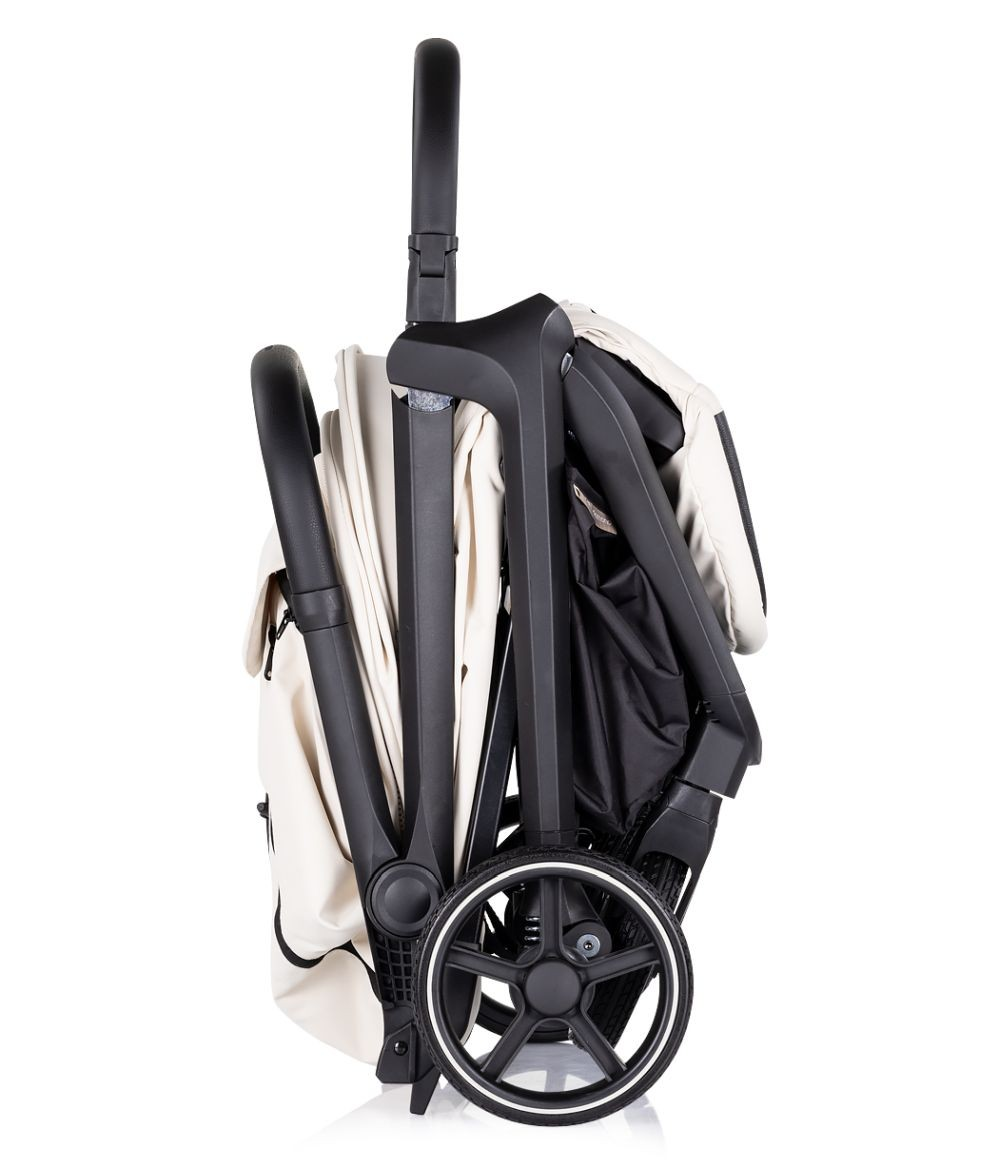 Ein zusammengeklappter beigefarbener Kinderwagen von der Seite, mit Griff, Rädern und Rahmen, vor Weiß.