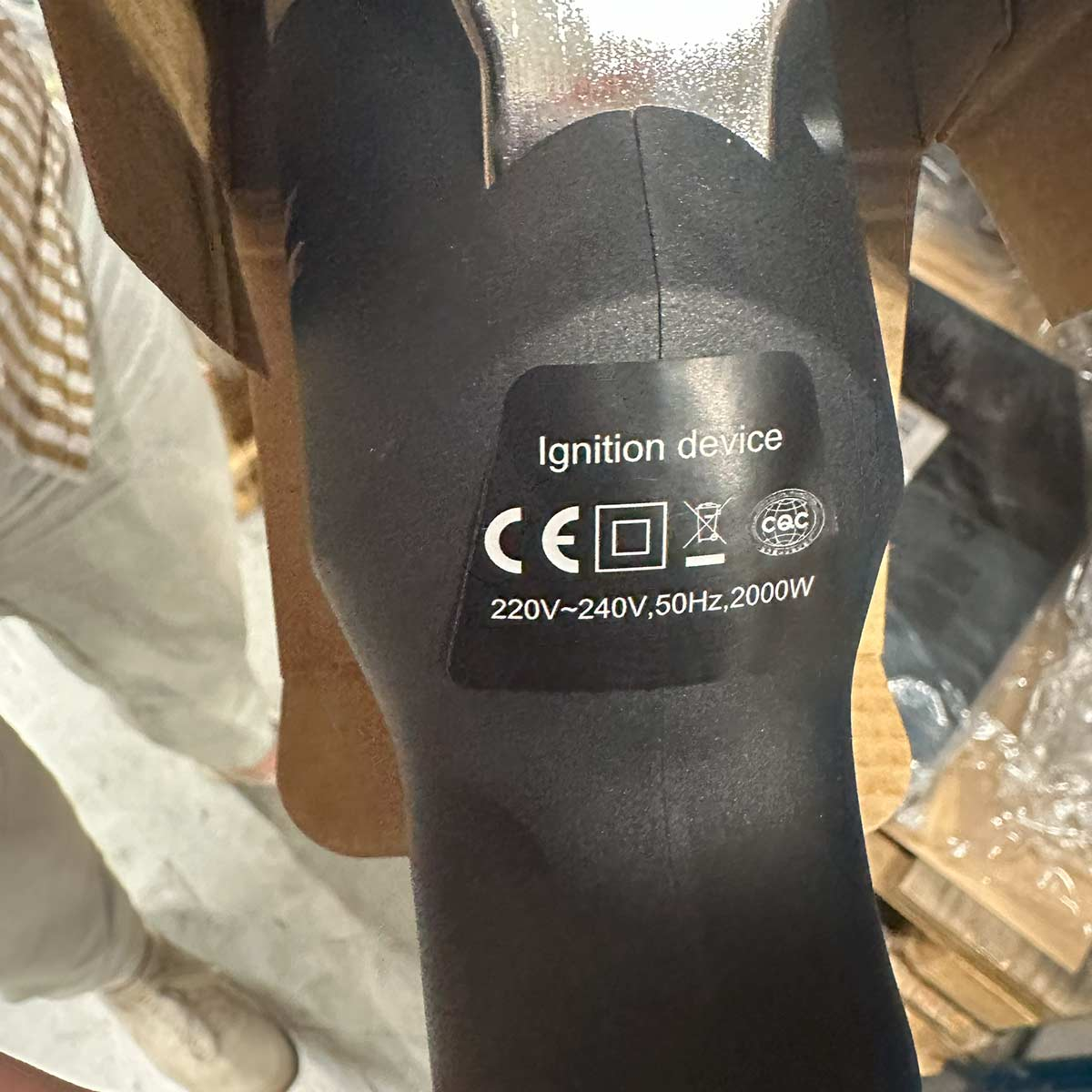 Close-up van een zwart ontstekingsapparaat met labels, symbolen en tekst.
