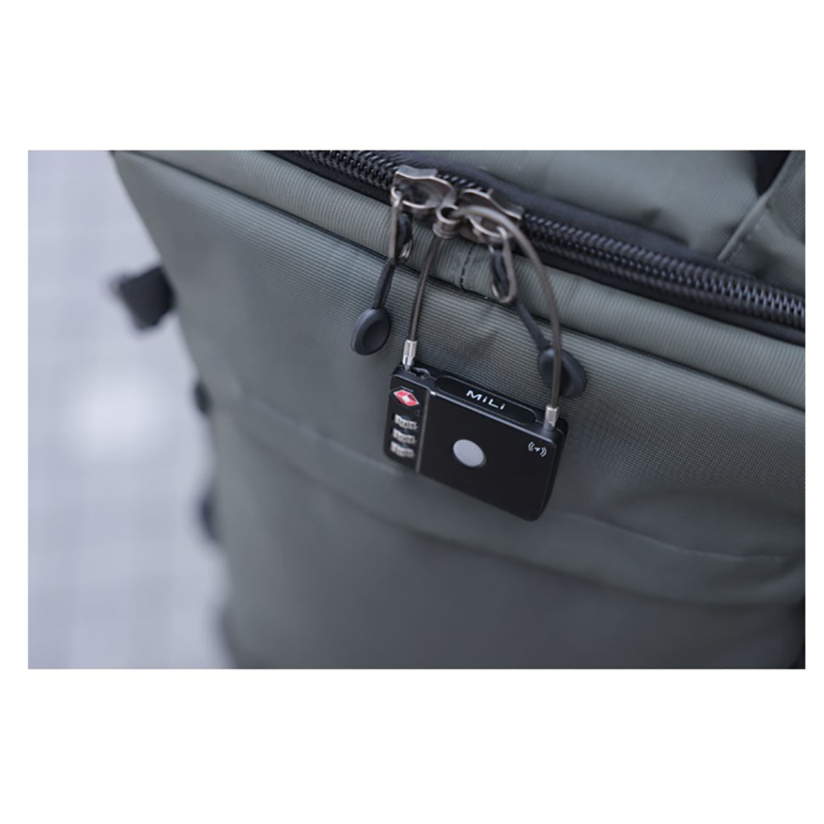 A black lock attached to a backpack. The lock has a number pad and the brand MILI.