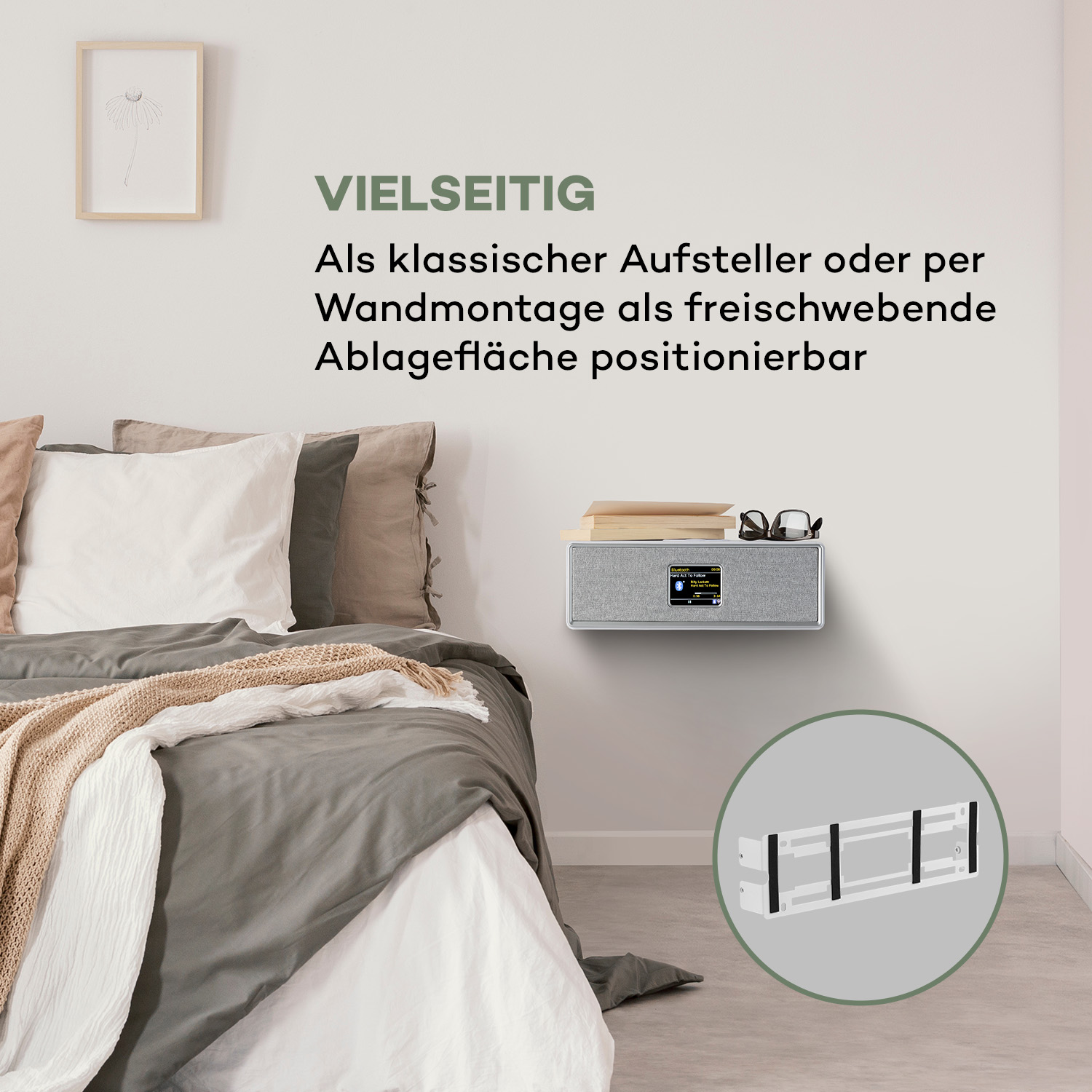 Graues Radio auf einem Wandregal mit Büchern und Brille. Ein Bett ist im Hintergrund.