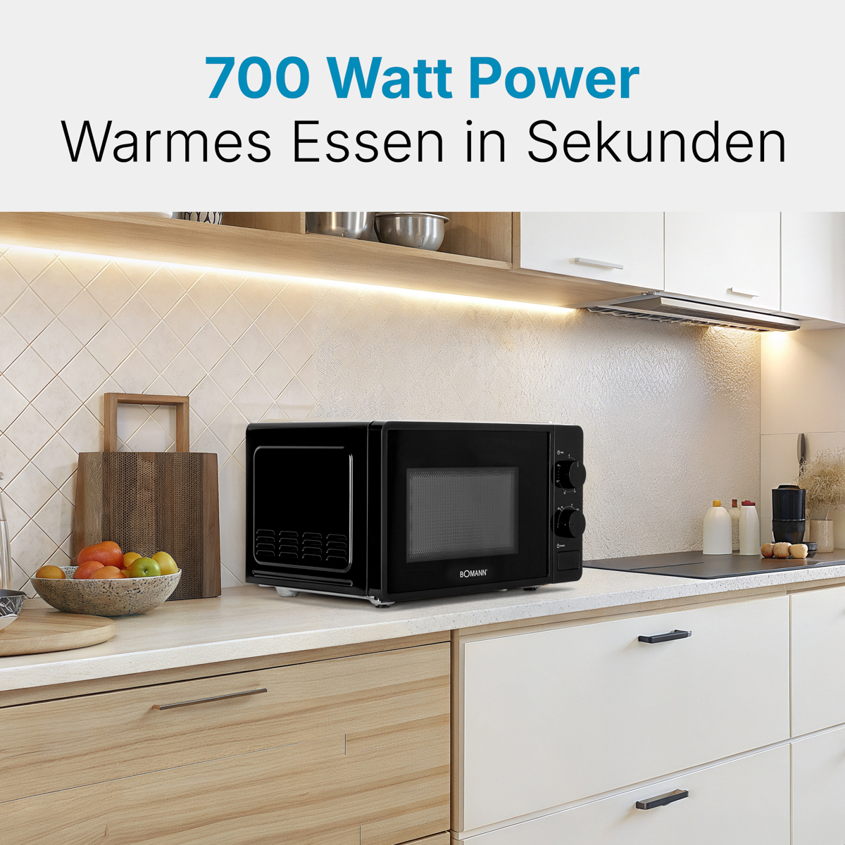 Czarna kuchenka mikrofalowa na blacie. Tekst: Moc 700 W. Ciepłe jedzenie w kilka sekund. Tło kuchni.