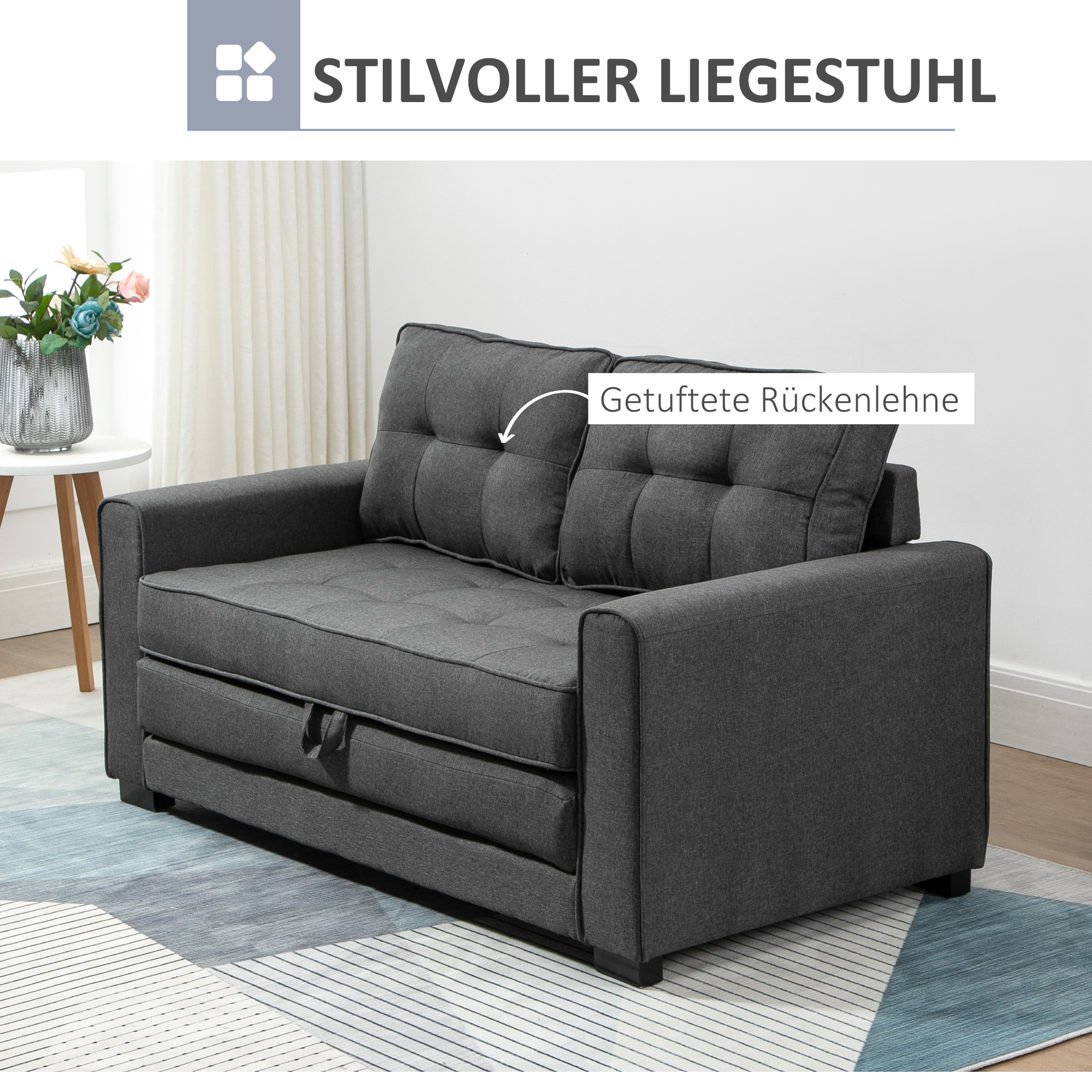 Graues Sofa auf einem Teppich, ein weißer Tisch mit Blumen und ein Gemälde. Das Sofa hat eine gesteppte Rückenlehne.