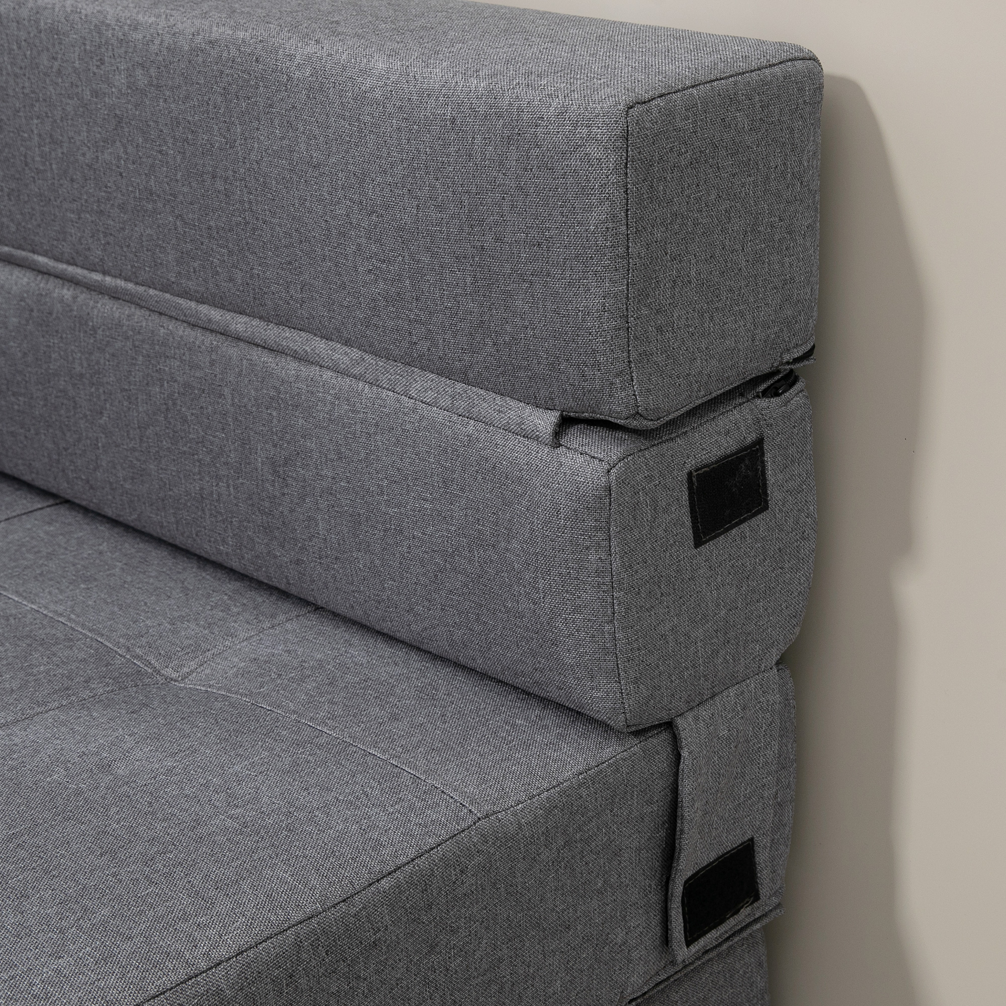 Nahaufnahme eines grauen Stoffsofas, das gestapelte Abschnitte und schwarze Eckbefestigungen zeigt.