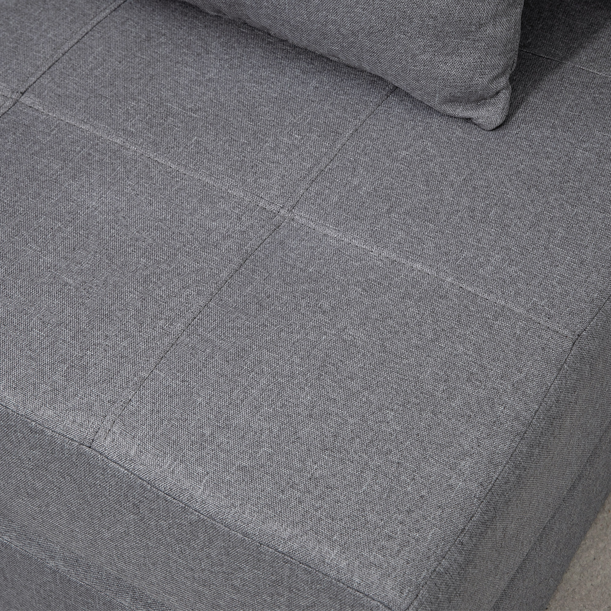 Nahaufnahme eines grauen Stoffsofas mit abgesteppten Quadraten. Zeigt Stoffdetails.