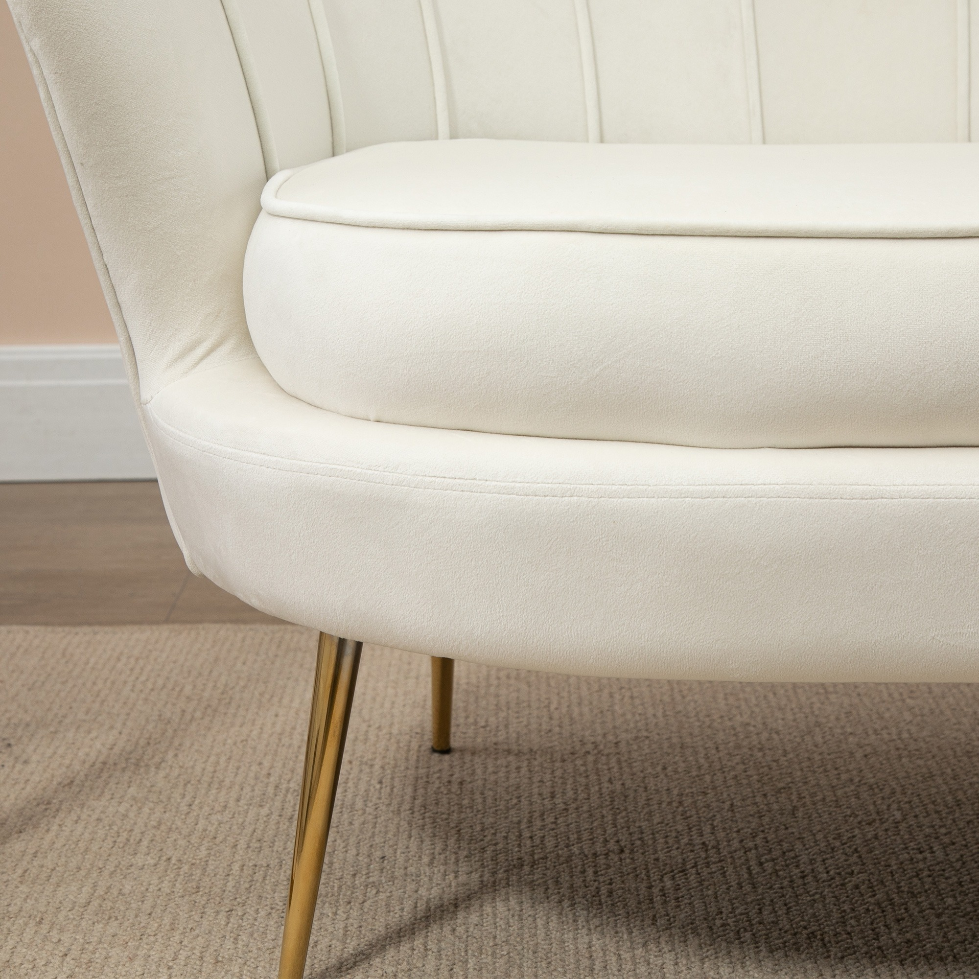 Nahaufnahme des cremefarbenen Loveseats, zeigt Sitzkissen und goldene Beine.