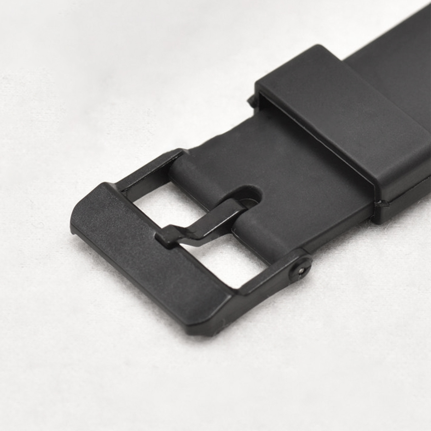 Nahaufnahme einer schwarzen Uhrenarmbandschließe auf weißer Oberfläche.