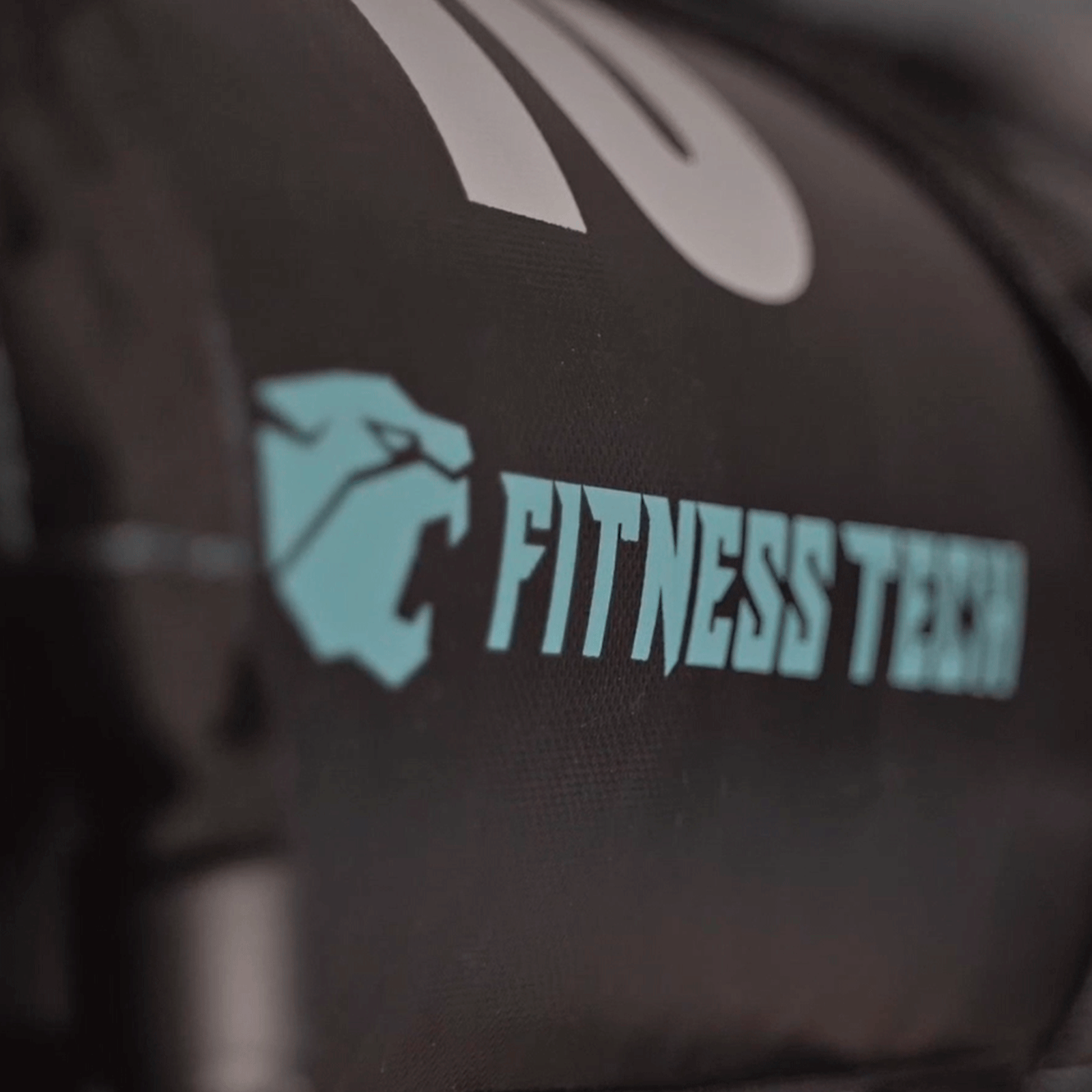 Primer plano de bolsa negra con logo Fitness Tech en aguamarina.