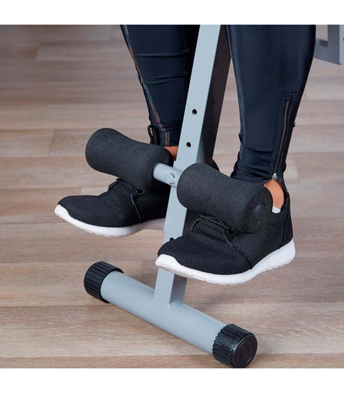 Piernas en un banco de pesas con soportes para los pies, usando zapatillas negras.