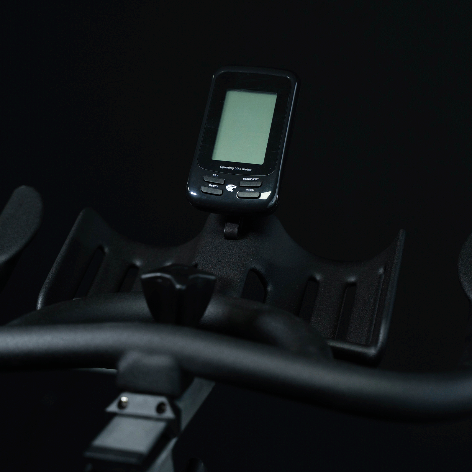 Primer plano de la consola de una bicicleta estática negra con pantalla y botones.