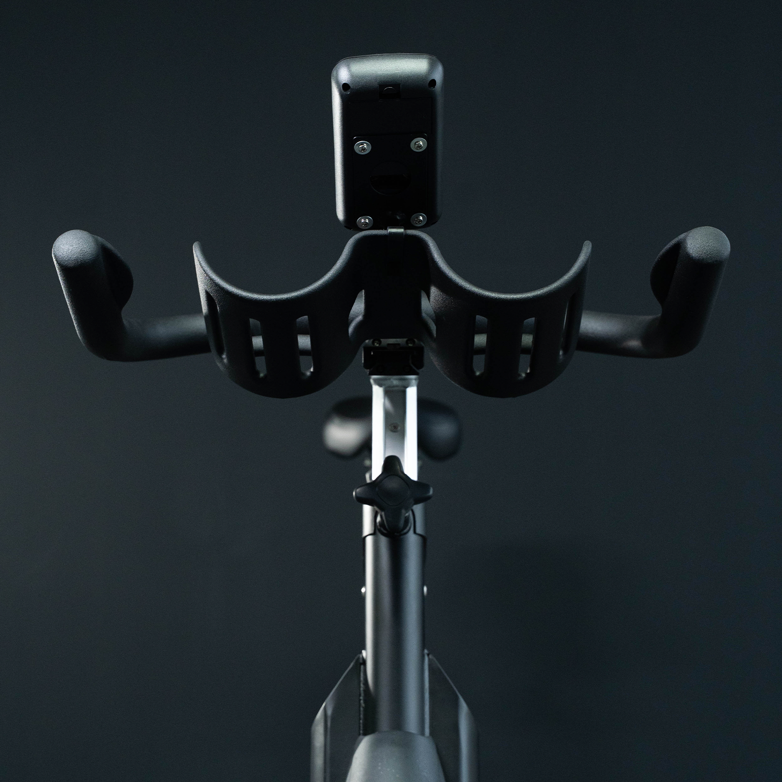 Manillar y pantalla de bicicleta estática. Color negro. Fondo oscuro. Marca Fitness Tech.
