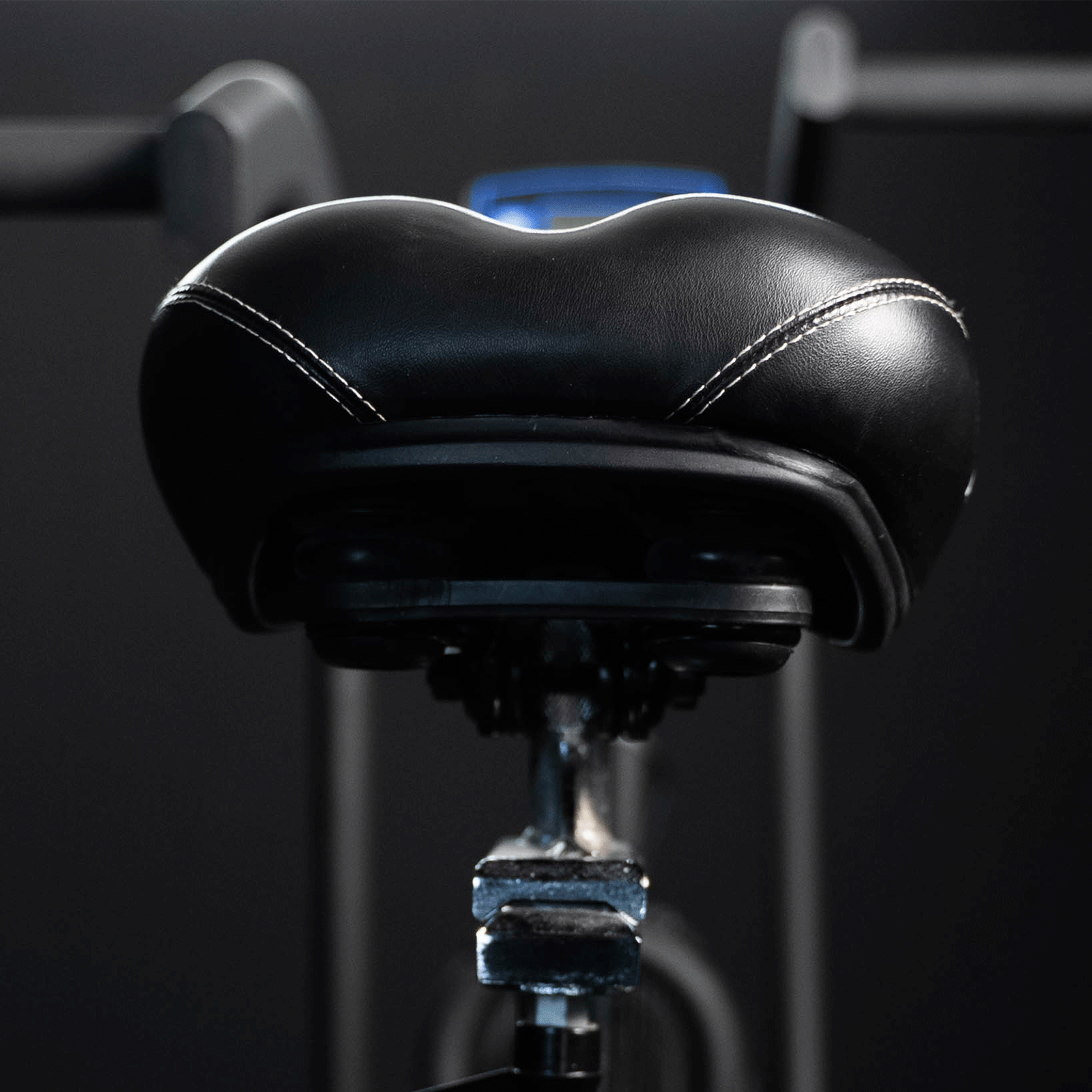 Sella per cyclette nera con cuciture bianche. Sfondo nero.