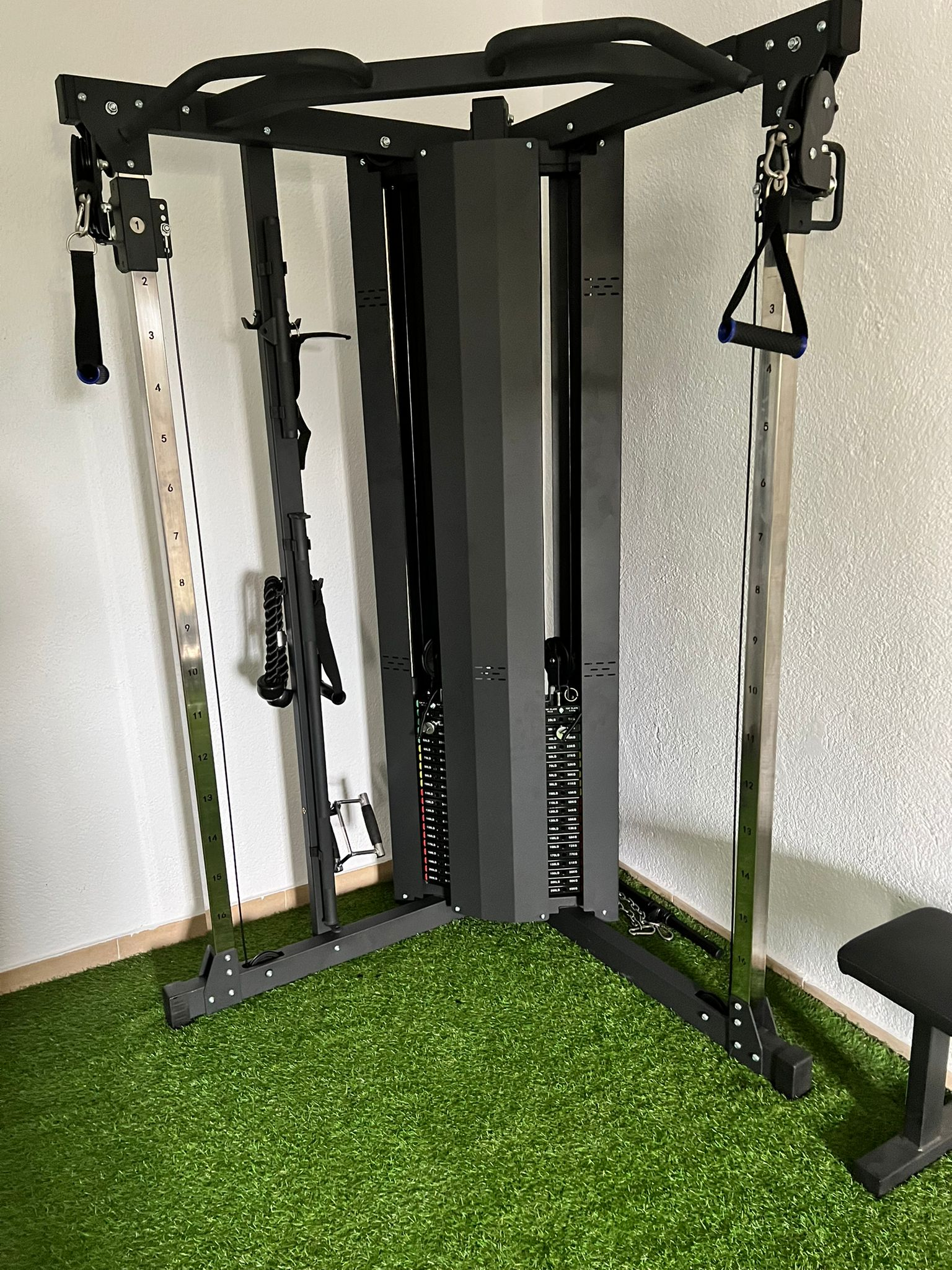 Máquina de cable de gimnasio en una habitación con suelo de césped verde.