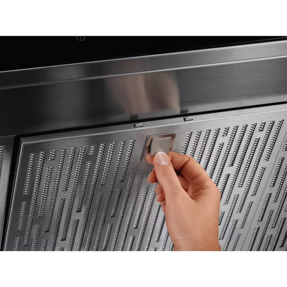 Una mano tira un pannello in acciaio inossidabile per rivelare un filtro perforato.