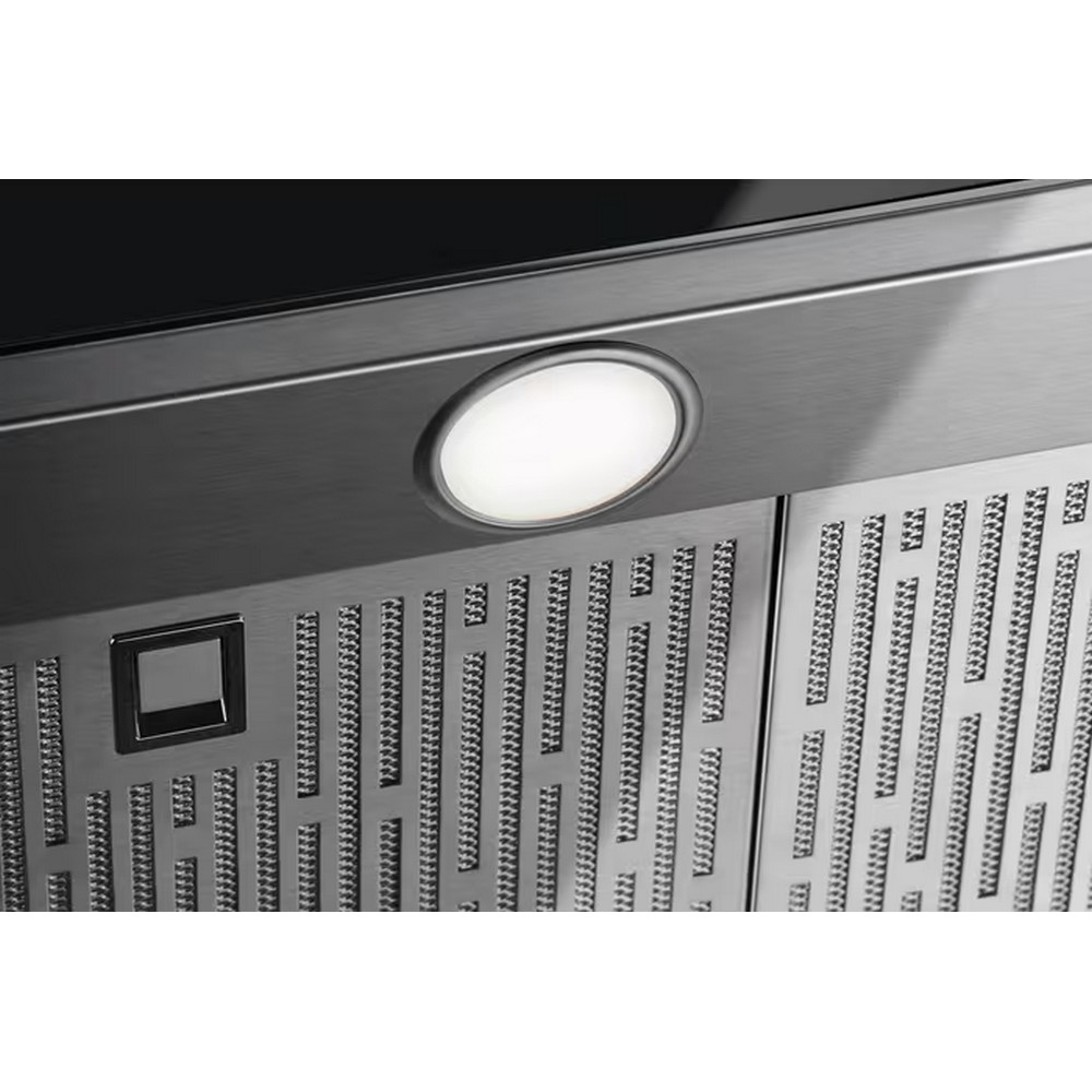 Primo piano di una cappa in acciaio inossidabile con luce brillante e griglia perforata.