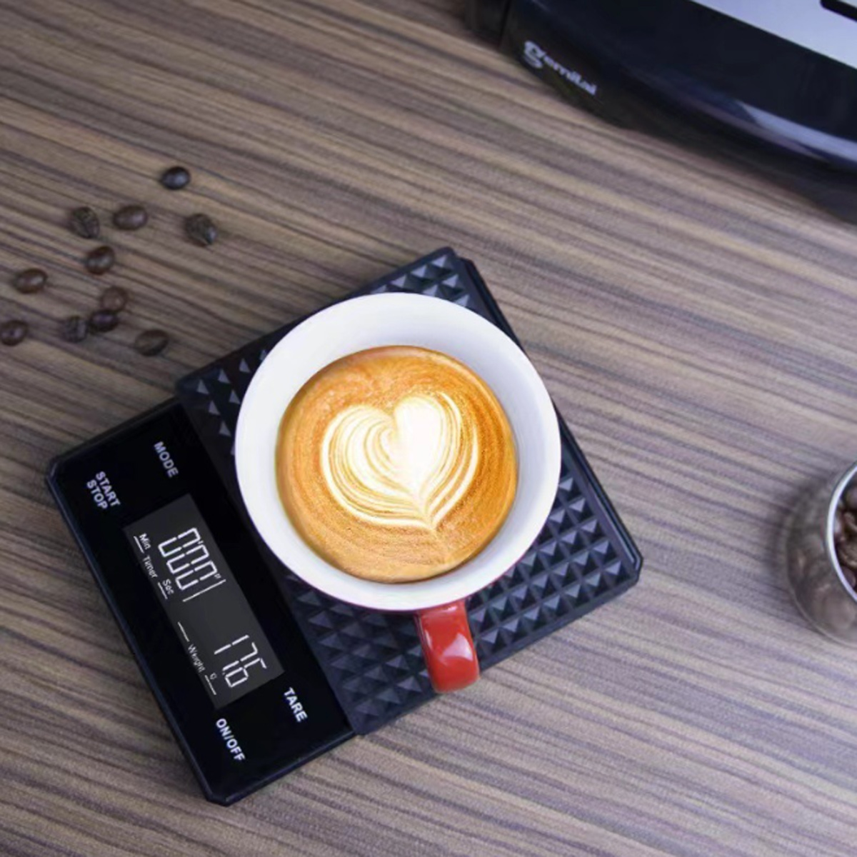 Schwarze digitale Küchenwaage mit einer Tasse Kaffee mit Herzmuster.