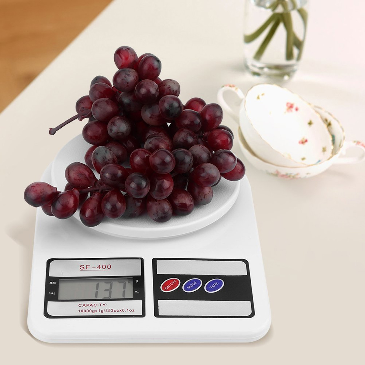 Weiße Digitalwaage mit Trauben, 137g. Display mit Schnell-, Modus- und Tara-Tasten.