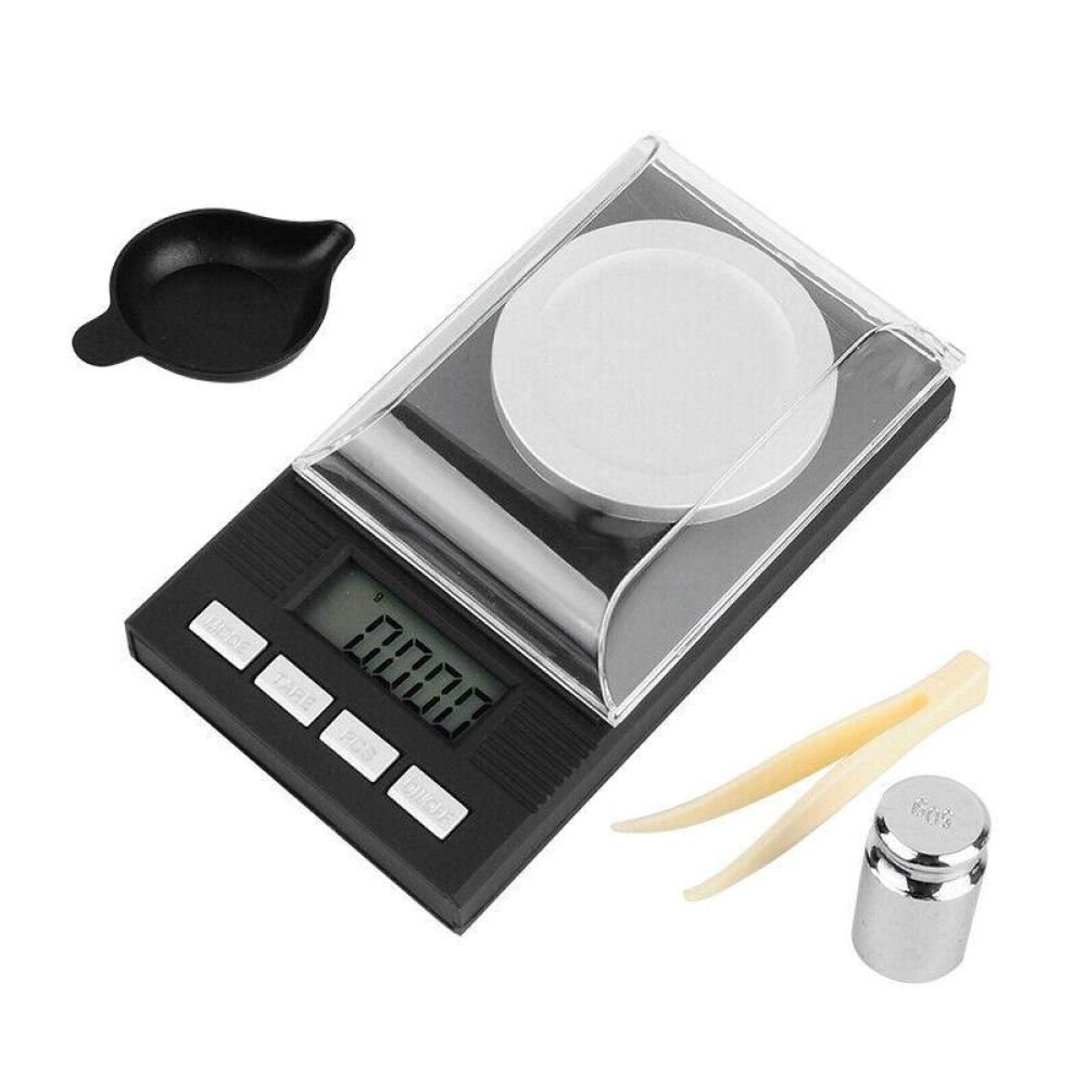 Schwarze Digitalwaage mit Zubehör: kleine Schale, Pinzette und Gewicht.