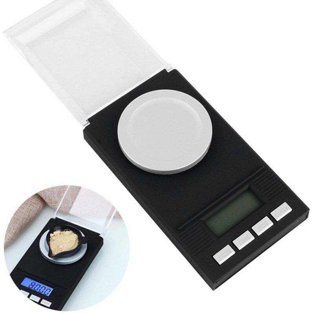 Eine kleine schwarze Digitalwaage mit geöffnetem Deckel. Eine kleine Schüssel mit braunem Pulver steht auf der Waagschale.