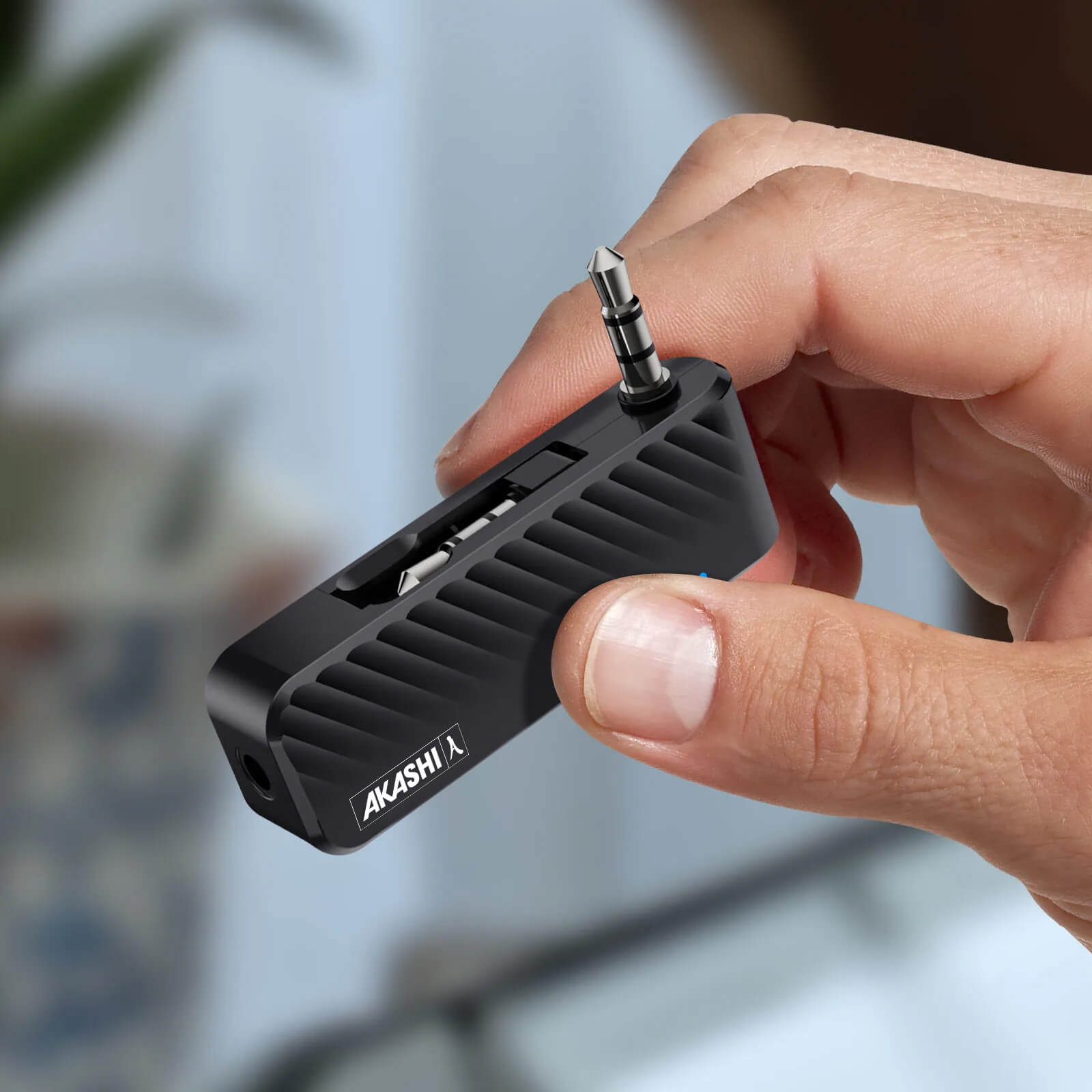 Un adattatore audio nero con jack da 3,5 mm e porta USB, tenuto in mano. Il marchio è Akashi.