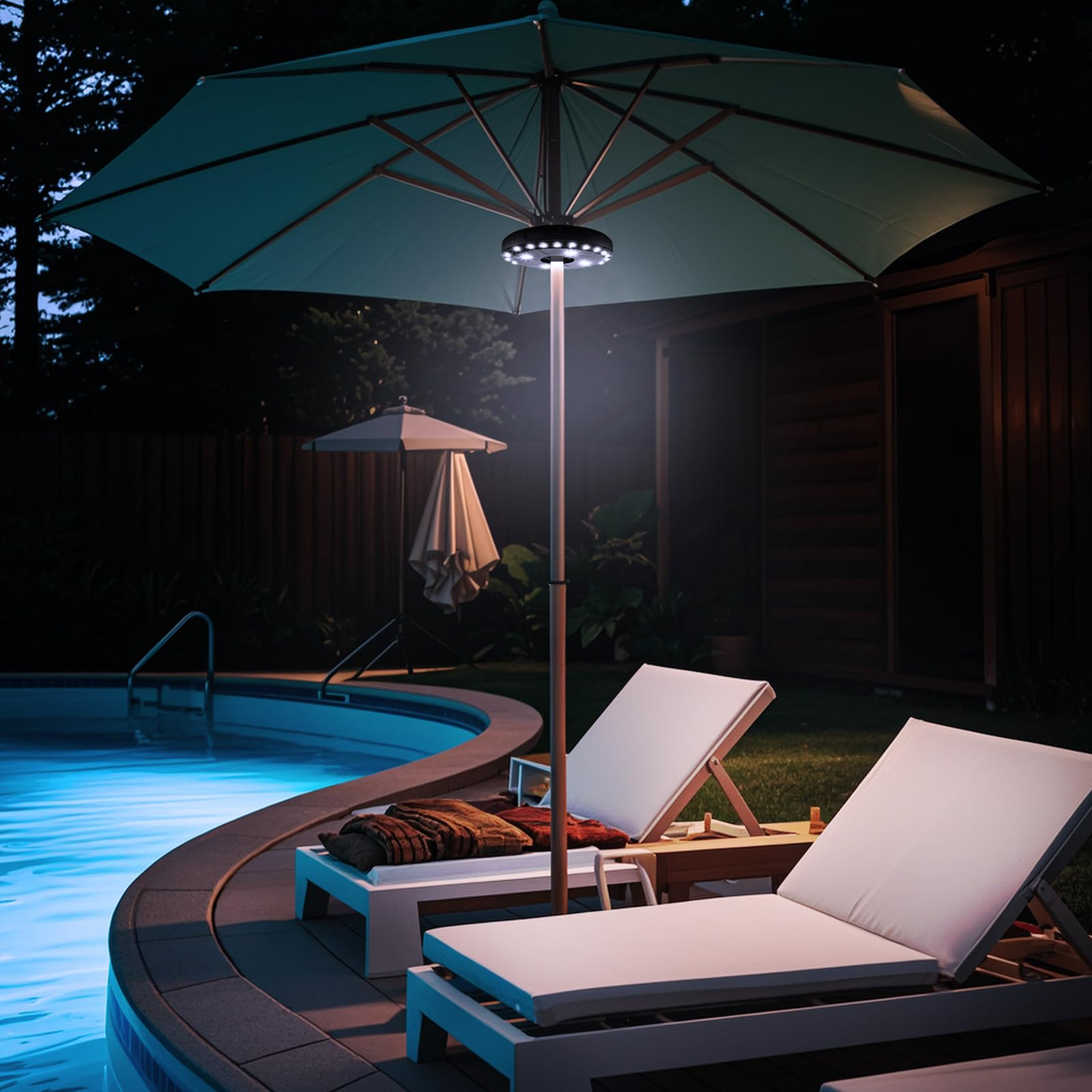 Nachtszene mit Pool und zwei Liegestühlen. Ein beleuchteter Schirm und ein dunkler Hintergrund mit Bäumen.