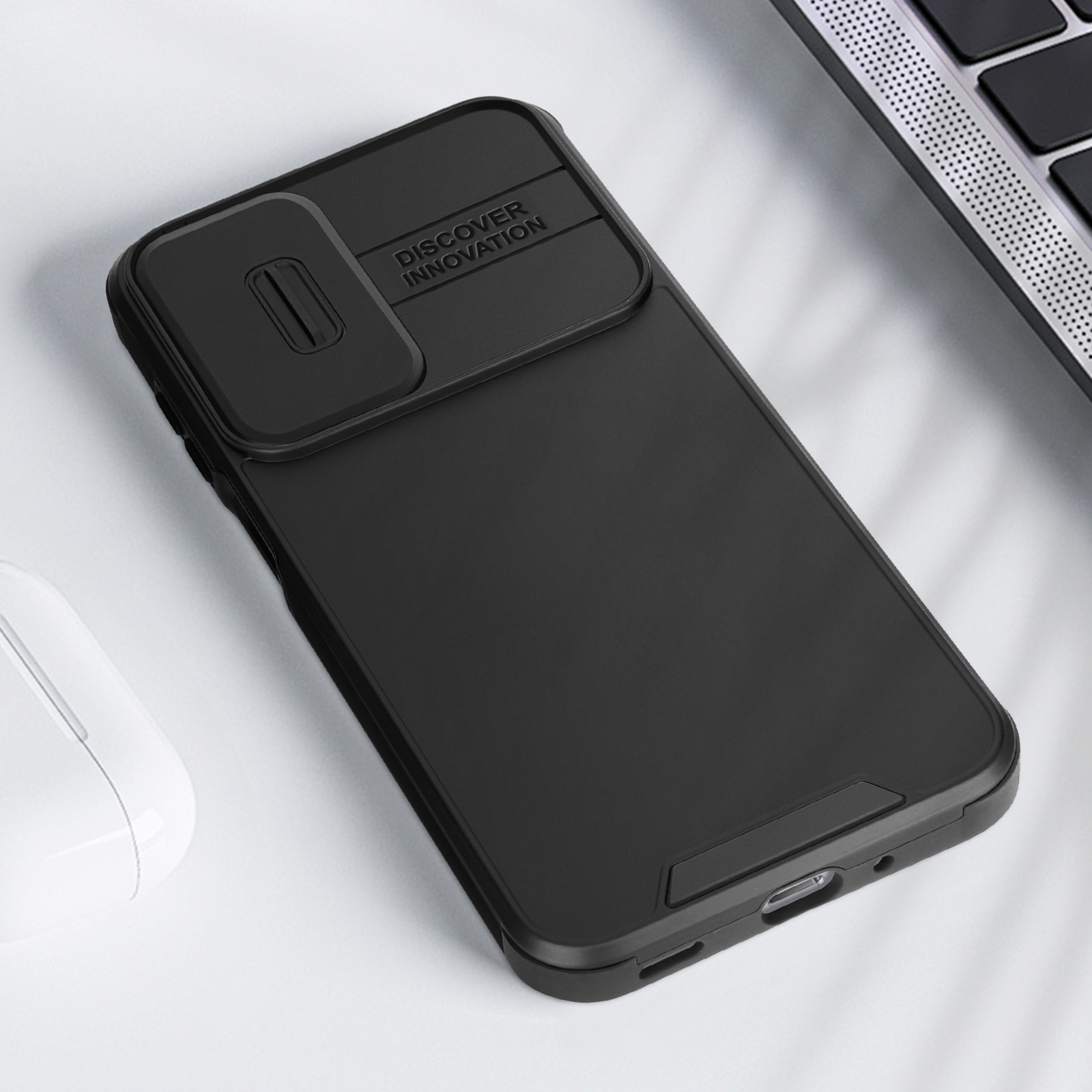 Custodia nera per telefono con copriobiettivo. Un mouse bianco è visibile sul tavolo.
