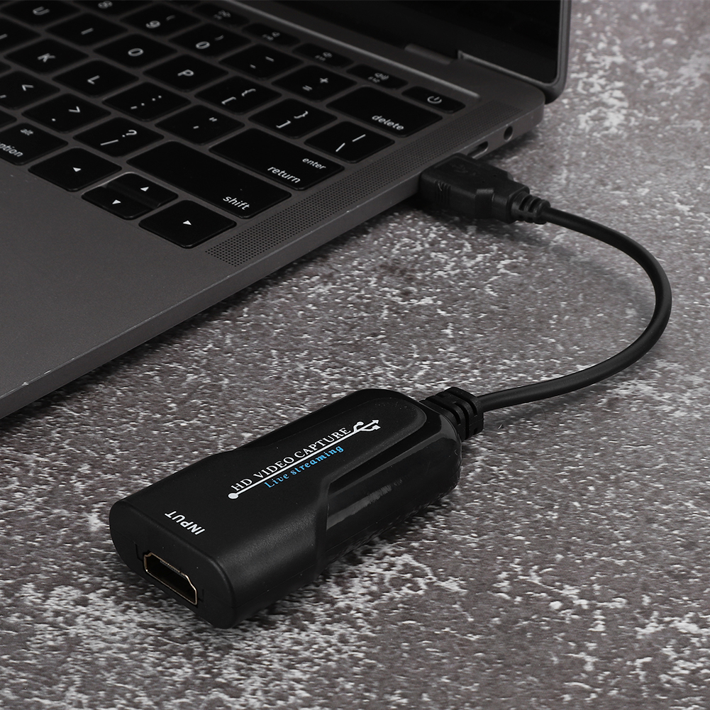 Schwarzes HDMI-Videoaufnahmegerät, das mit einem Laptop verbunden ist. Graue Oberfläche.