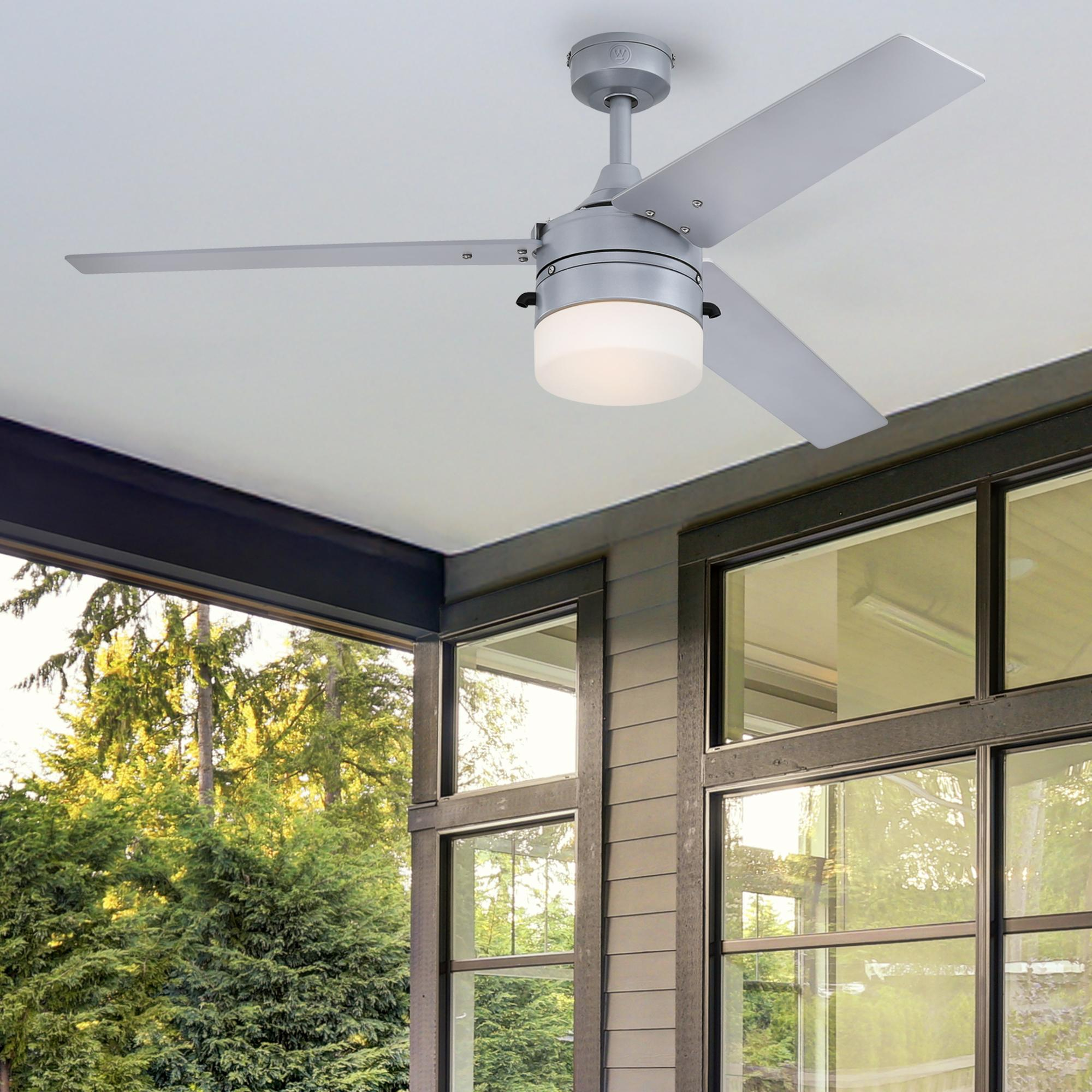 Deckenventilator auf einer Veranda. Der Hintergrund zeigt einen grünen Garten und Fenster.