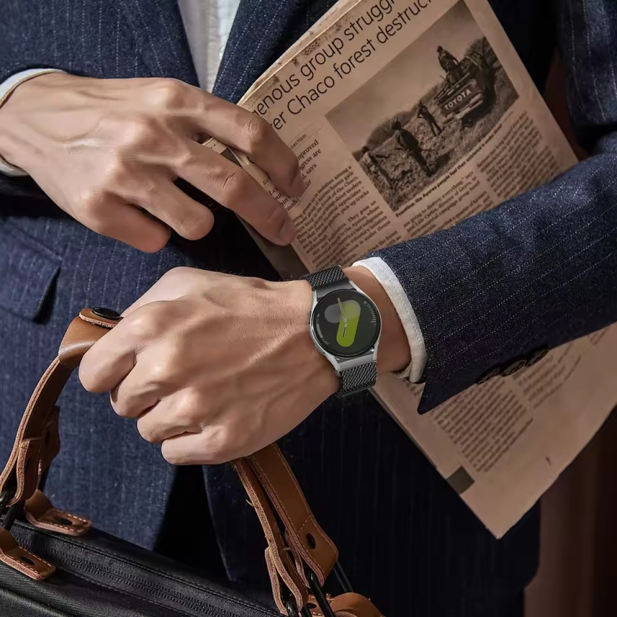 Un uomo in giacca e cravatta tiene un giornale e un orologio da polso con schermo verde.