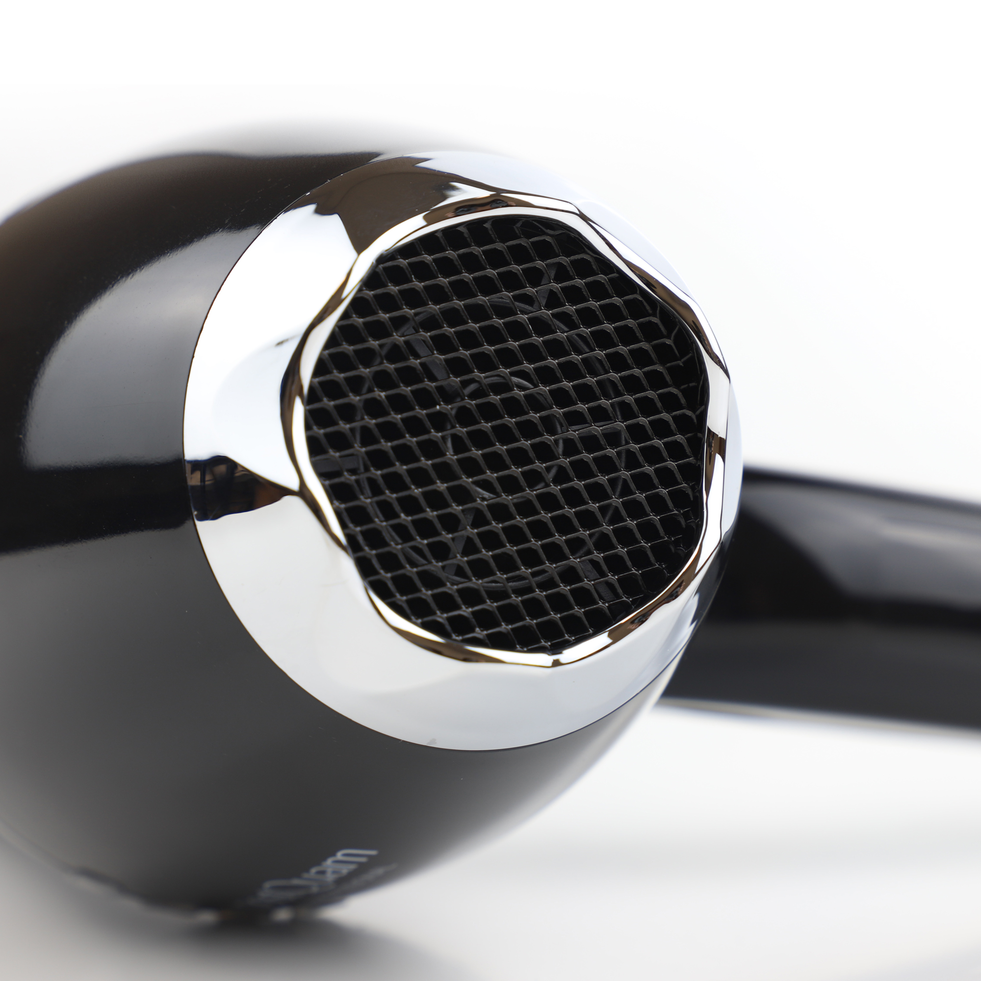 Czarna suszarka do włosów, zbliżenie. Chromowany pierścień wokół wylotu powietrza. Białe tło.