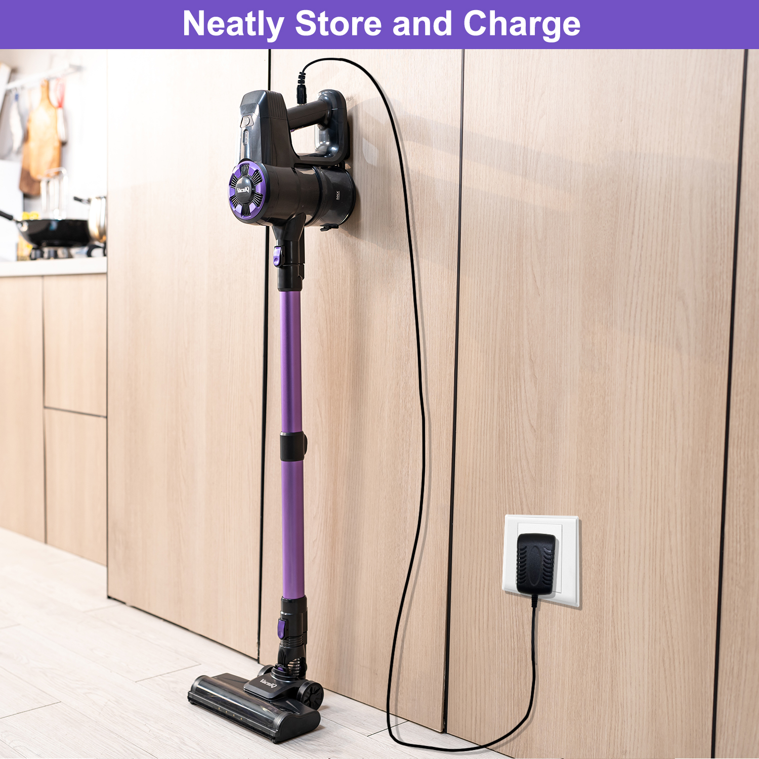 Purple and black cordless vacuum cleaner plugged into a wall outlet, charging. Set against a wooden wall.