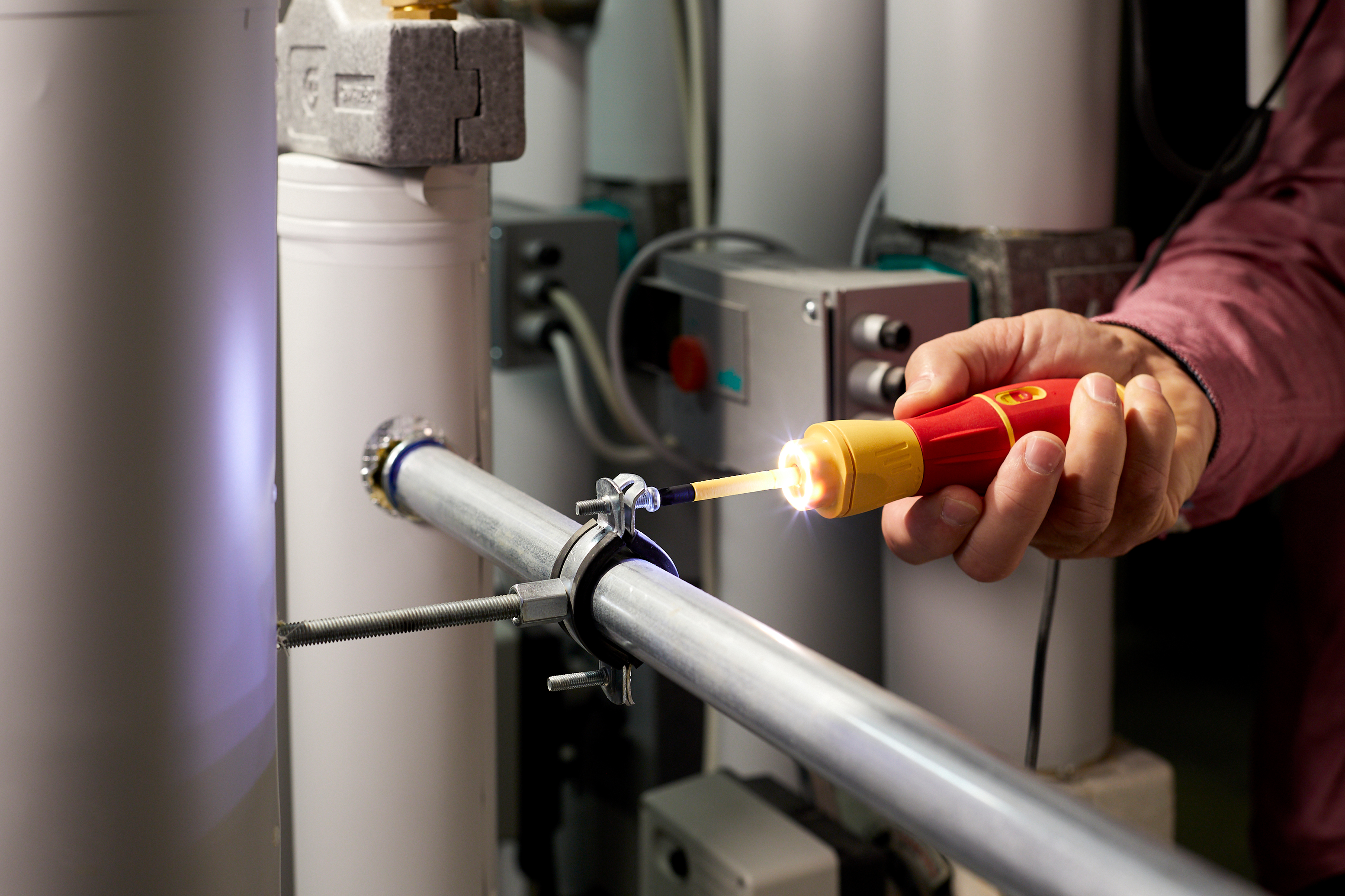 Osoba używająca czerwono-żółtego testera na metalowej rurze. Jasne światło.