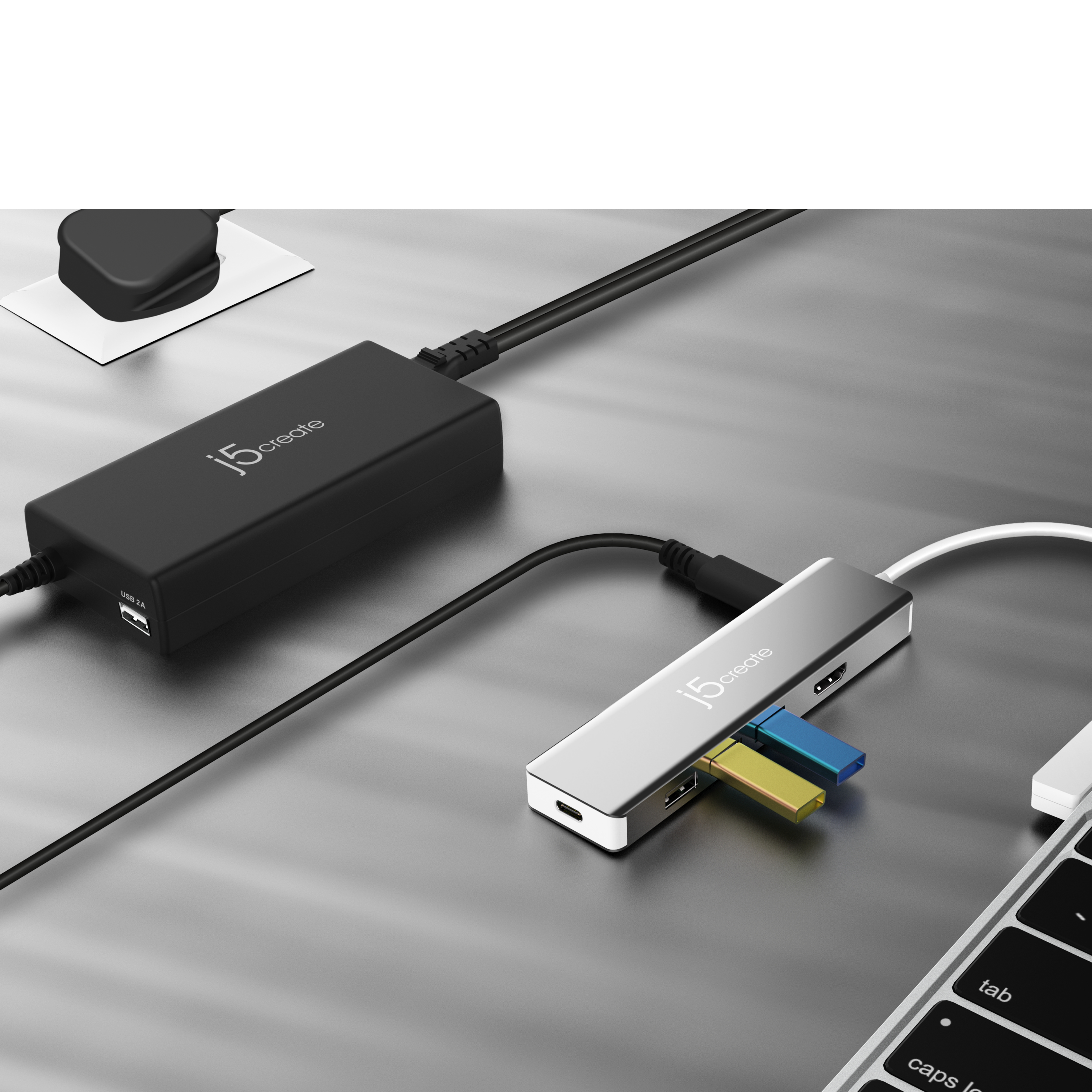 Schwarzer Hub mit USB-Anschlüssen, verbunden mit Netzteil und Laptop. Silberne Oberfläche.
