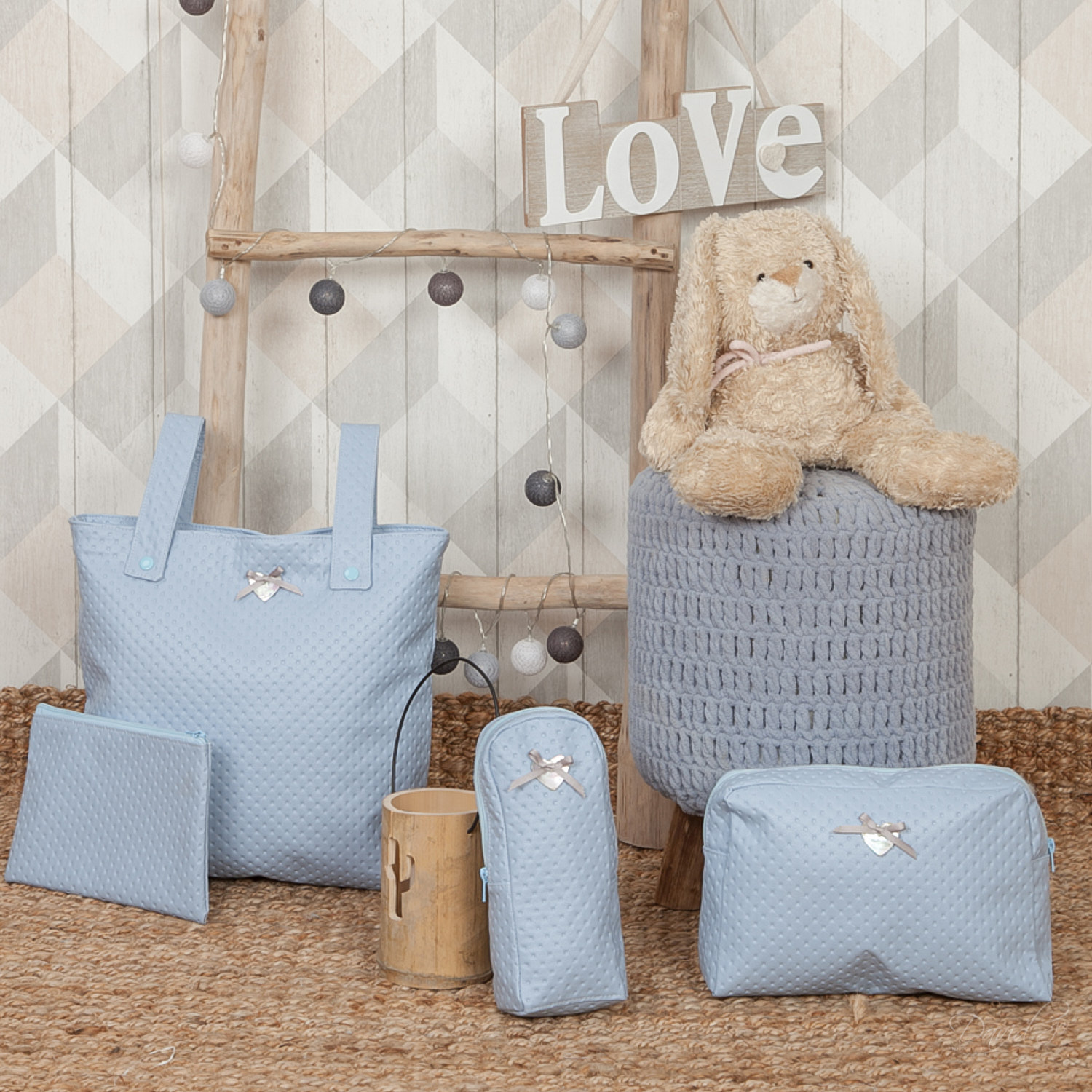 Artículos para bebés: un bolso tote, un bolso, un estuche y un bolso cambiador, todos azules, colocados sobre una alfombra.