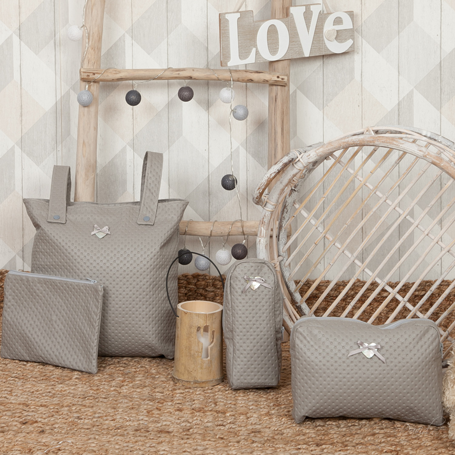 Conjunto gris de artículos para bebés, incluyendo un bolso, un neceser y una almohada. Escalera de madera.