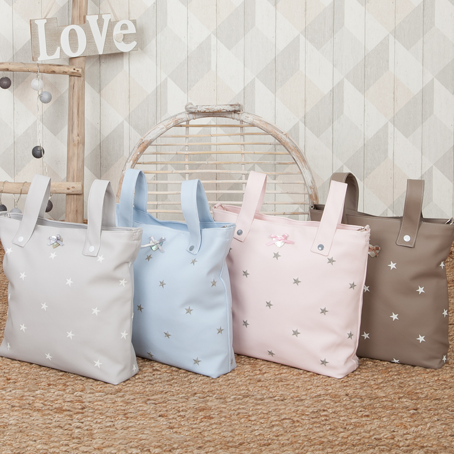Cuatro bolsos de bebé con estrellas, asas y lazos en la parte delantera.