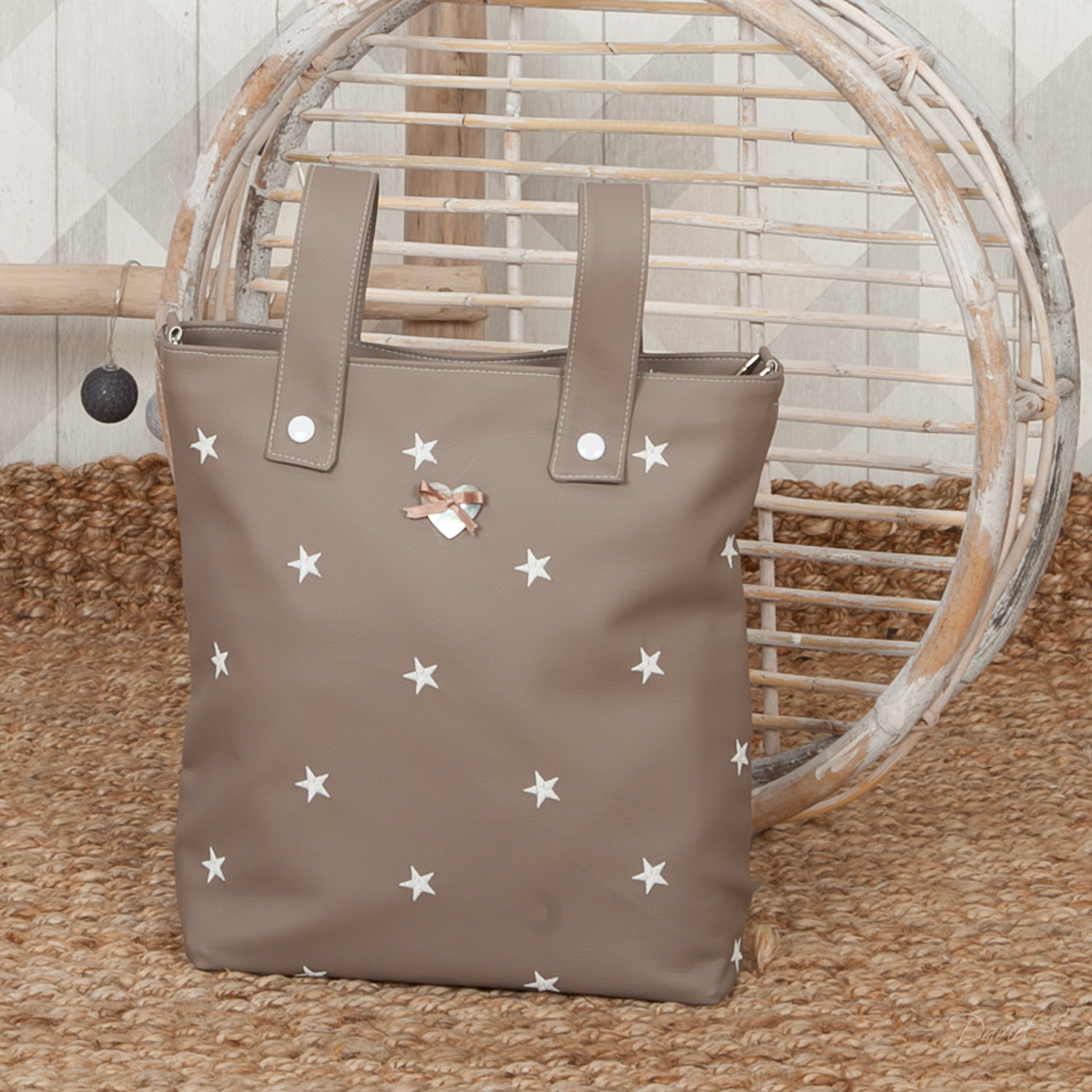 Bolso tote topo con estrellas blancas. En una alfombra beige junto a una silla.