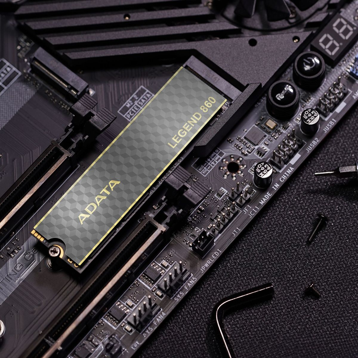 ADATA Legend 860 SSD zainstalowany na płycie głównej. Złoto i szarość, czarne tło.