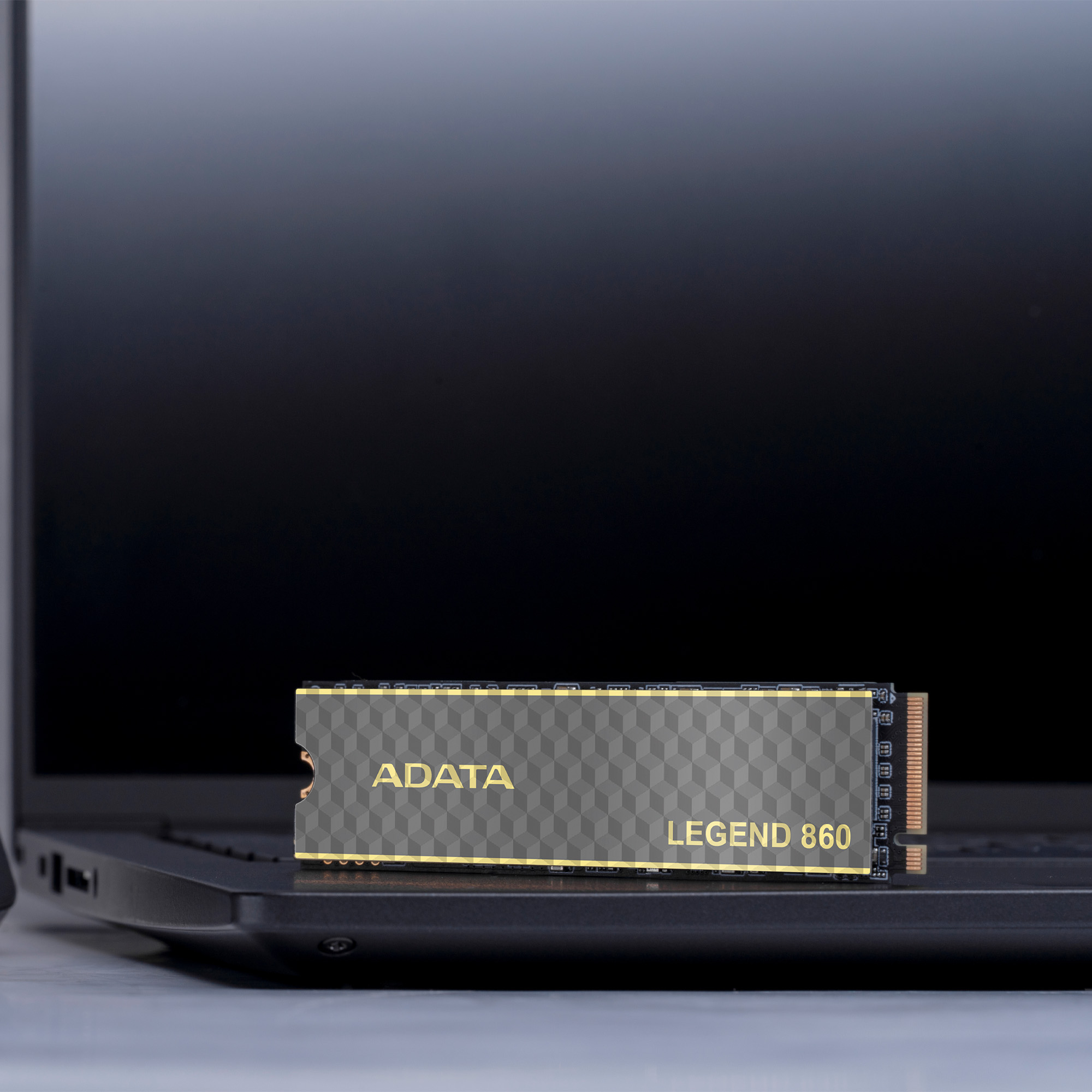 ADATA Legend 860 SSD na klawiaturze laptopa. Czarny SSD ze złotymi akcentami.