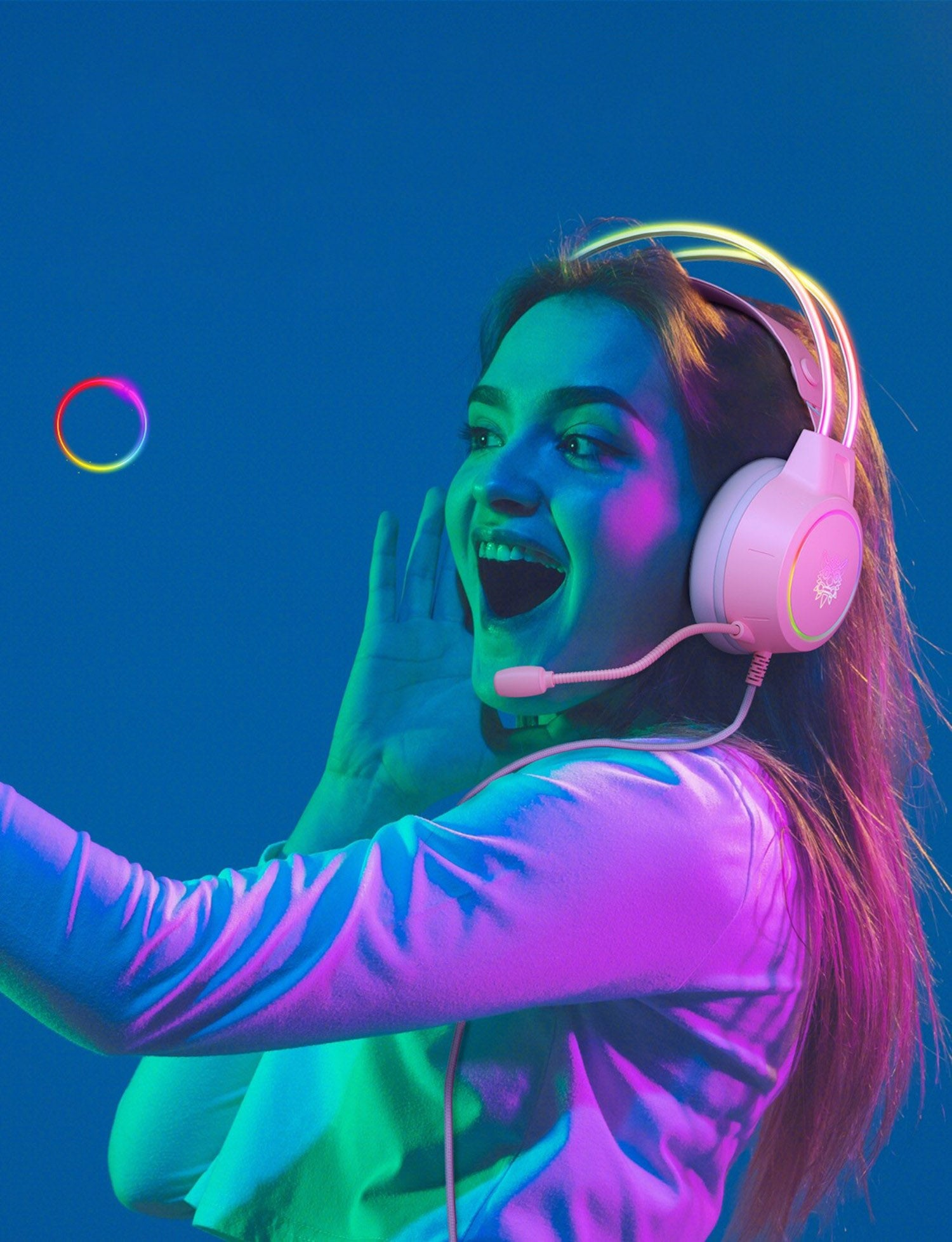 Donna con cuffie da gaming rosa, sorridente, con illuminazione al neon e un anello fluttuante.