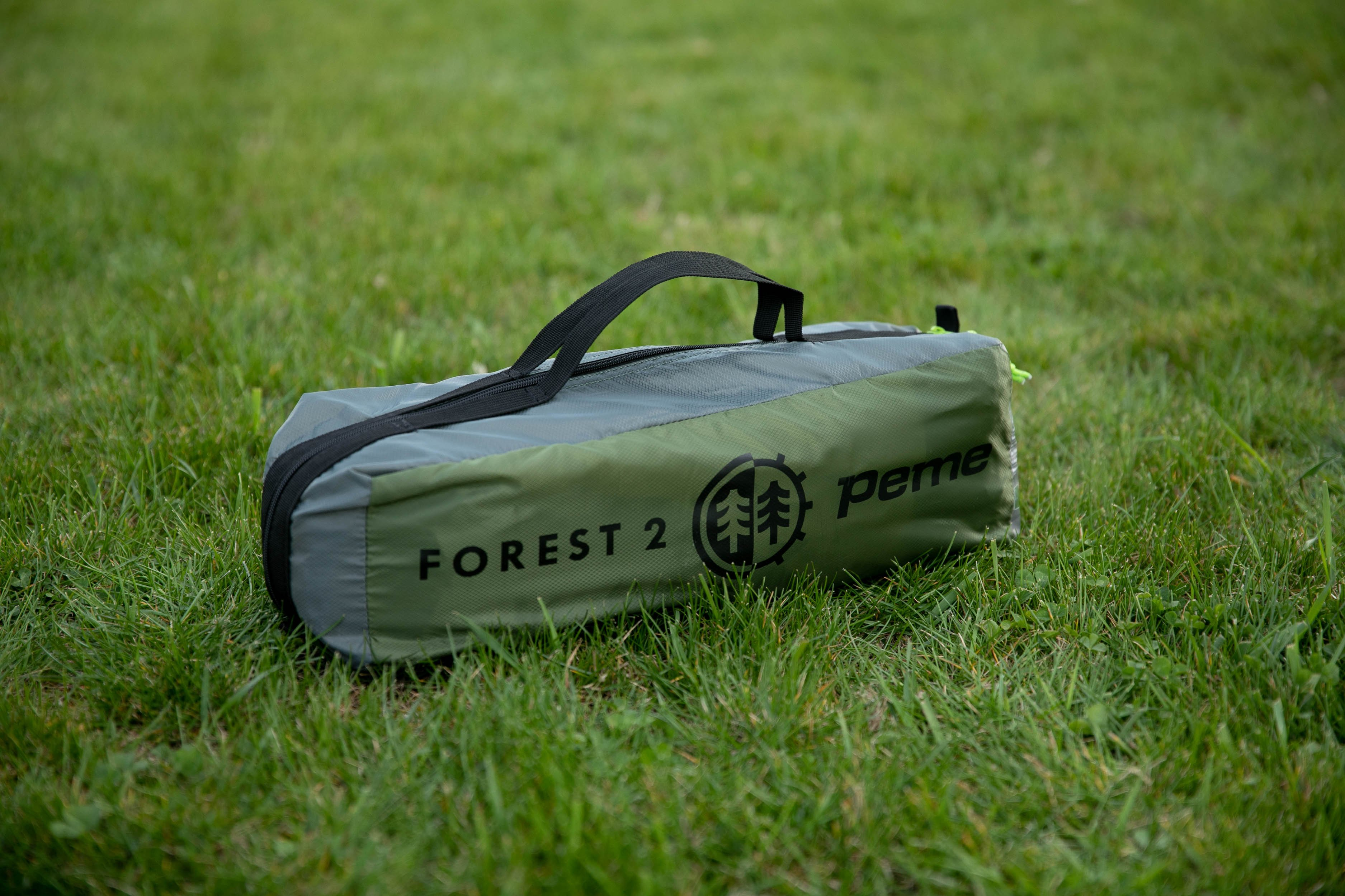 Una bolsa de tienda verde y gris con las palabras 'FOREST 2' y un logotipo de árbol sobre hierba.