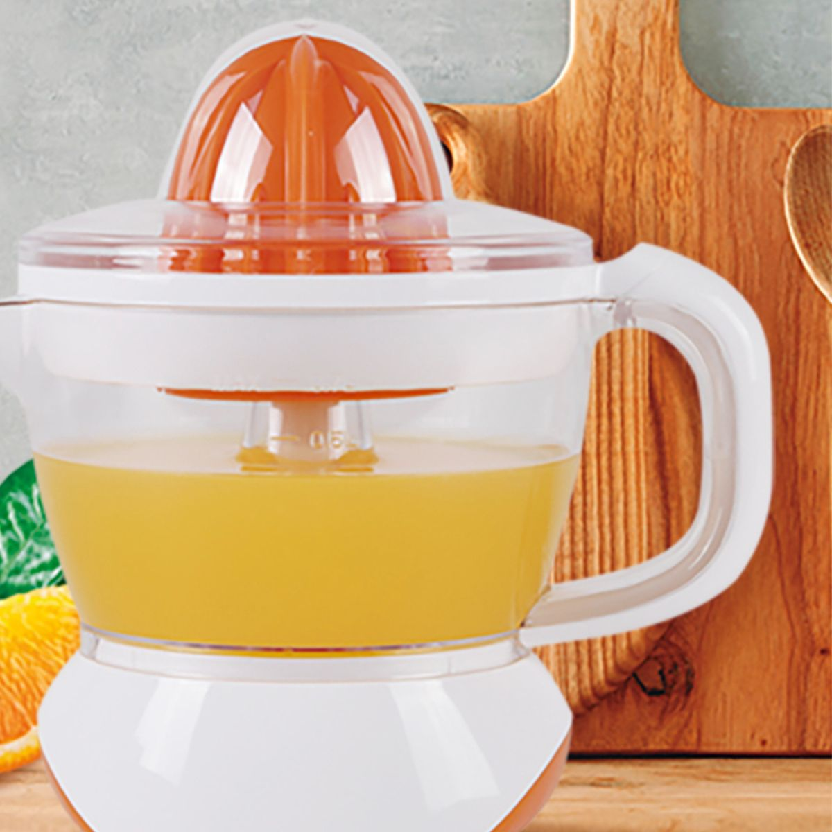 Exprimidor eléctrico con zumo de naranja. Blanco y naranja, con una tabla de cortar de madera en el fondo.