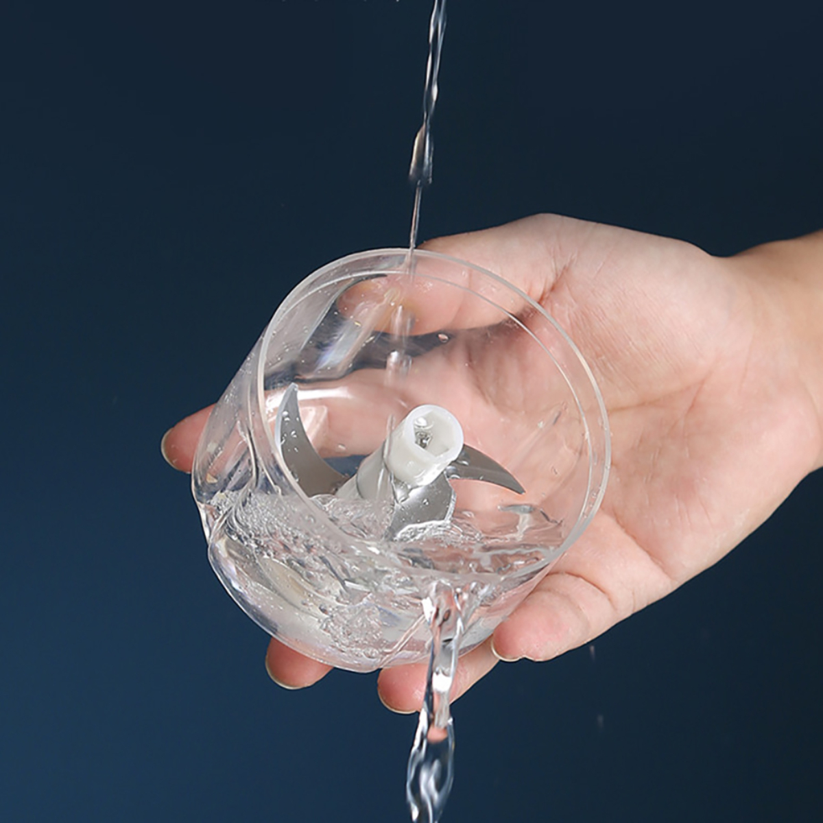 Agua vertiéndose en una picadora de alimentos con cuchillas dentro.