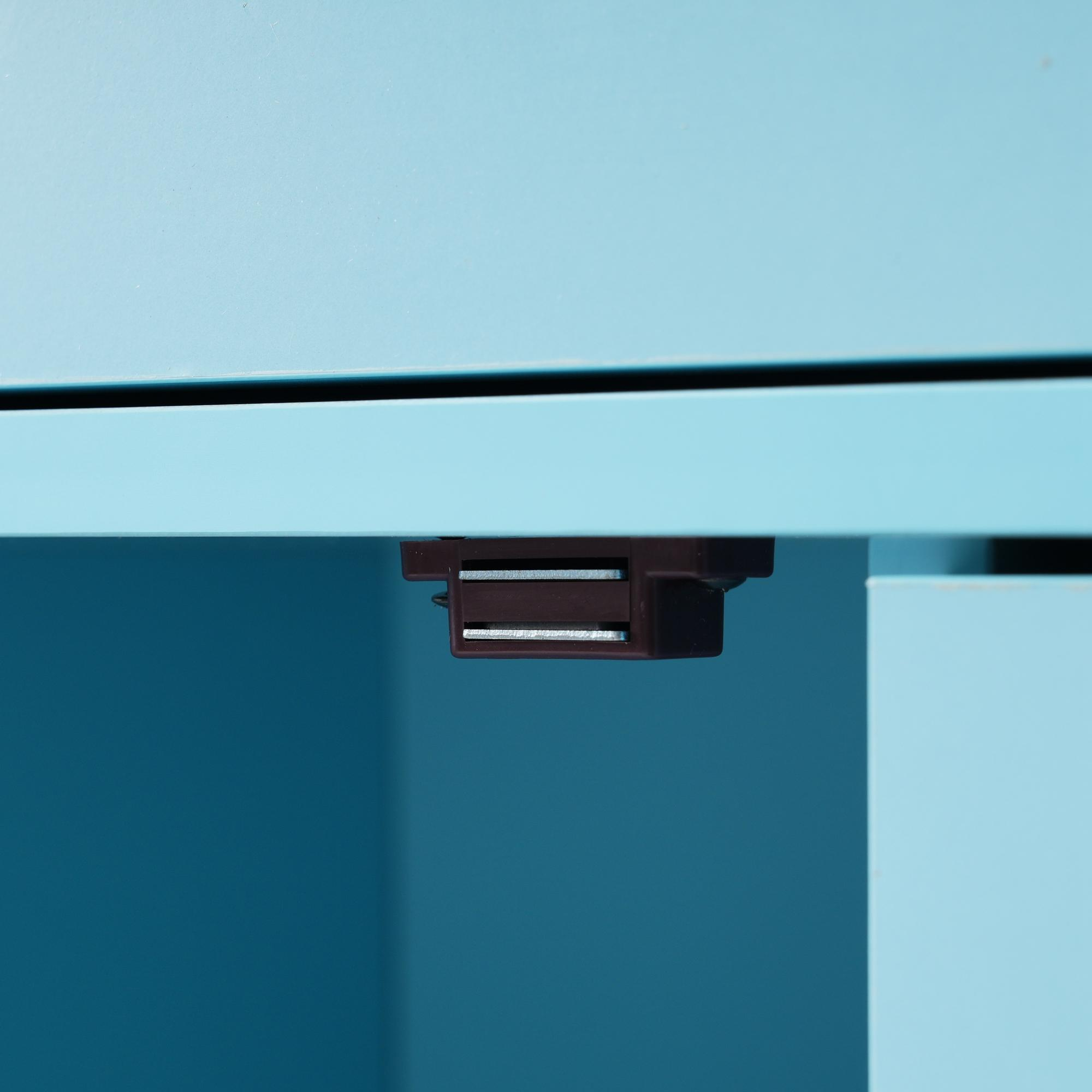 Nahaufnahme eines magnetischen Türverschlusses an einem hellblauen Schrank, dunkelbraun.