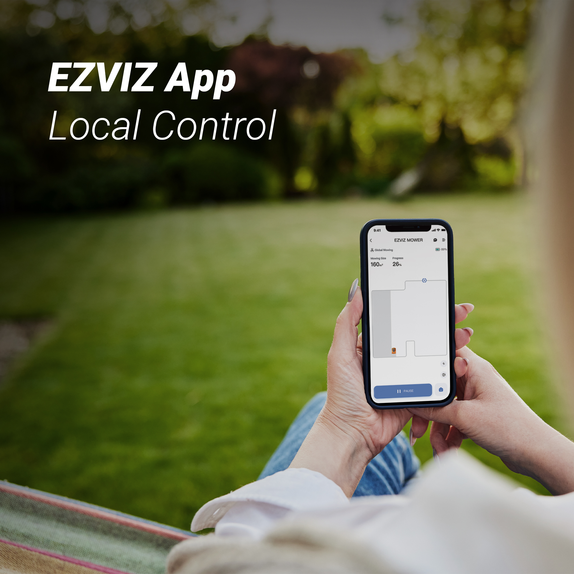 Una donna tiene in mano uno smartphone che mostra un'app per tosaerba sullo sfondo di un giardino.