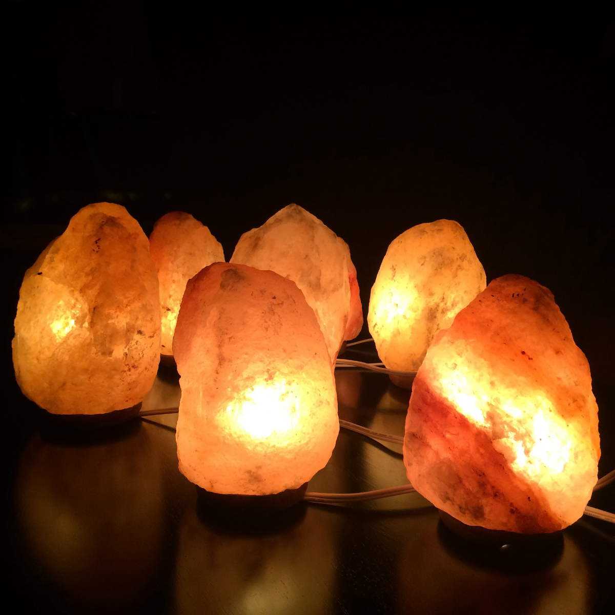 Varias lámparas de sal brillantes sobre una superficie oscura, juntas.