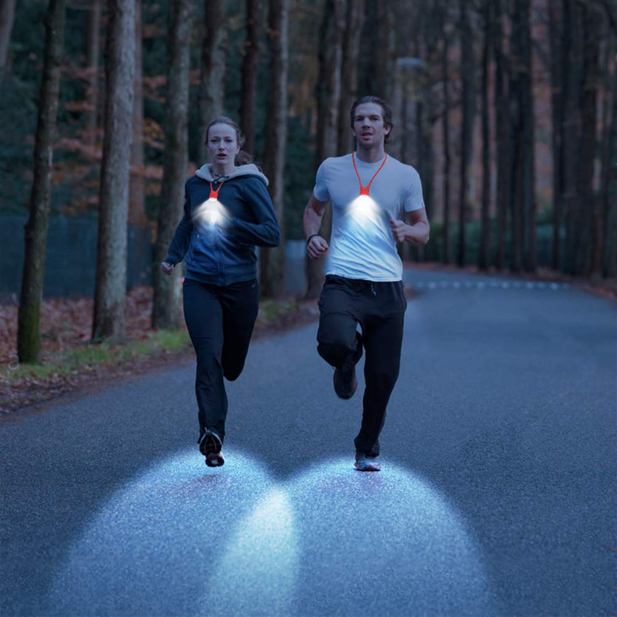 Dos personas corriendo en una carretera de noche, con luces en el cuello, iluminando el suelo.
